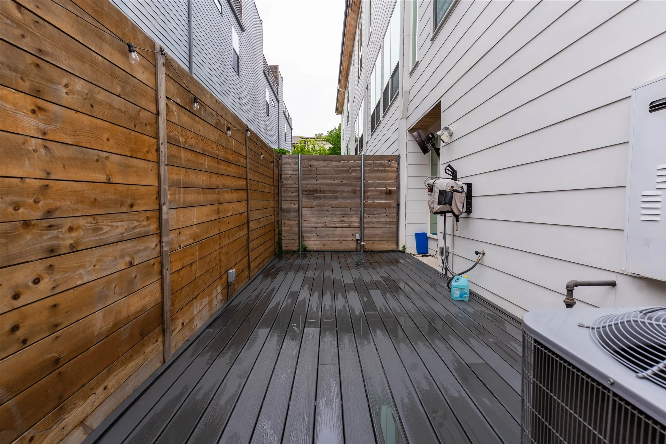 Private exterior decking featuring dark composite planks and warm-toned wood fencing