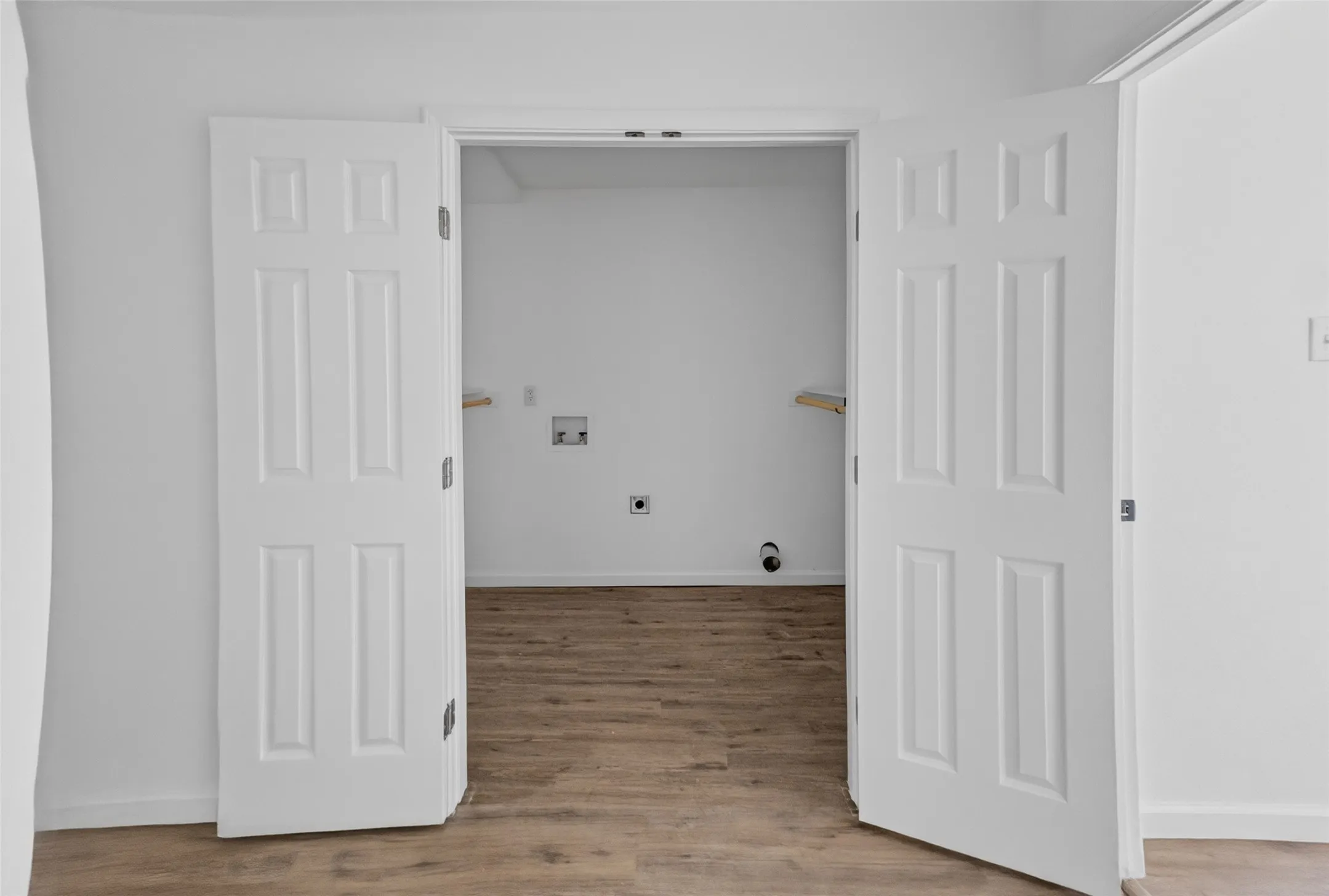 Utility area featuring wood-finish flooring, white walls, and a built-in shelf