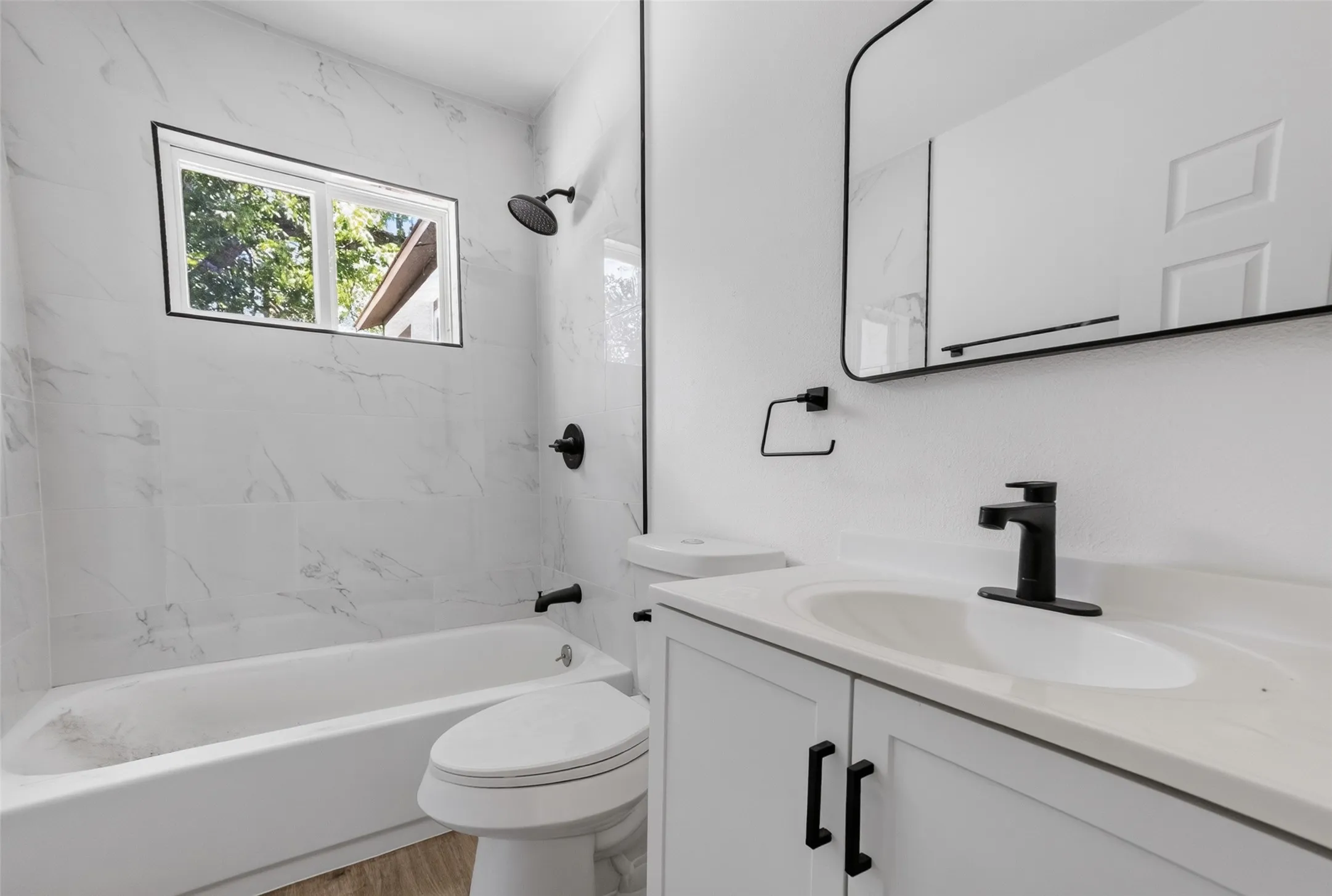 Bathroom featuring a white bathtub, toilet, and vanity with an integrated sink