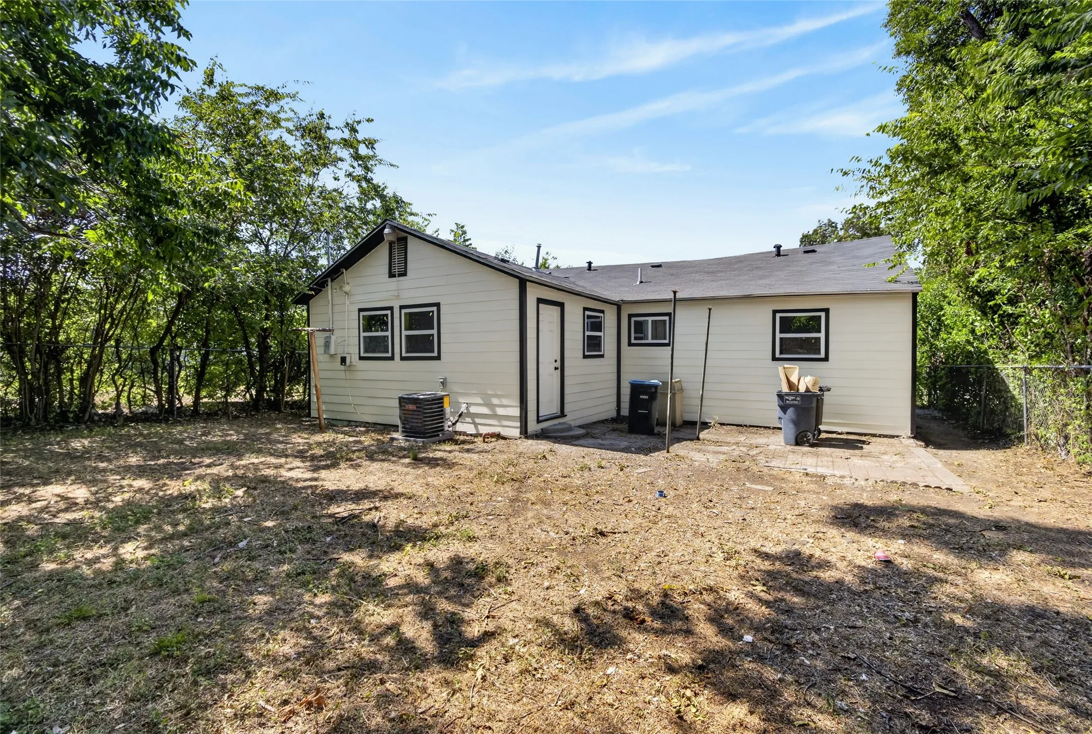 Rear exterior with light-colored siding, black trim windows, and a dark roof