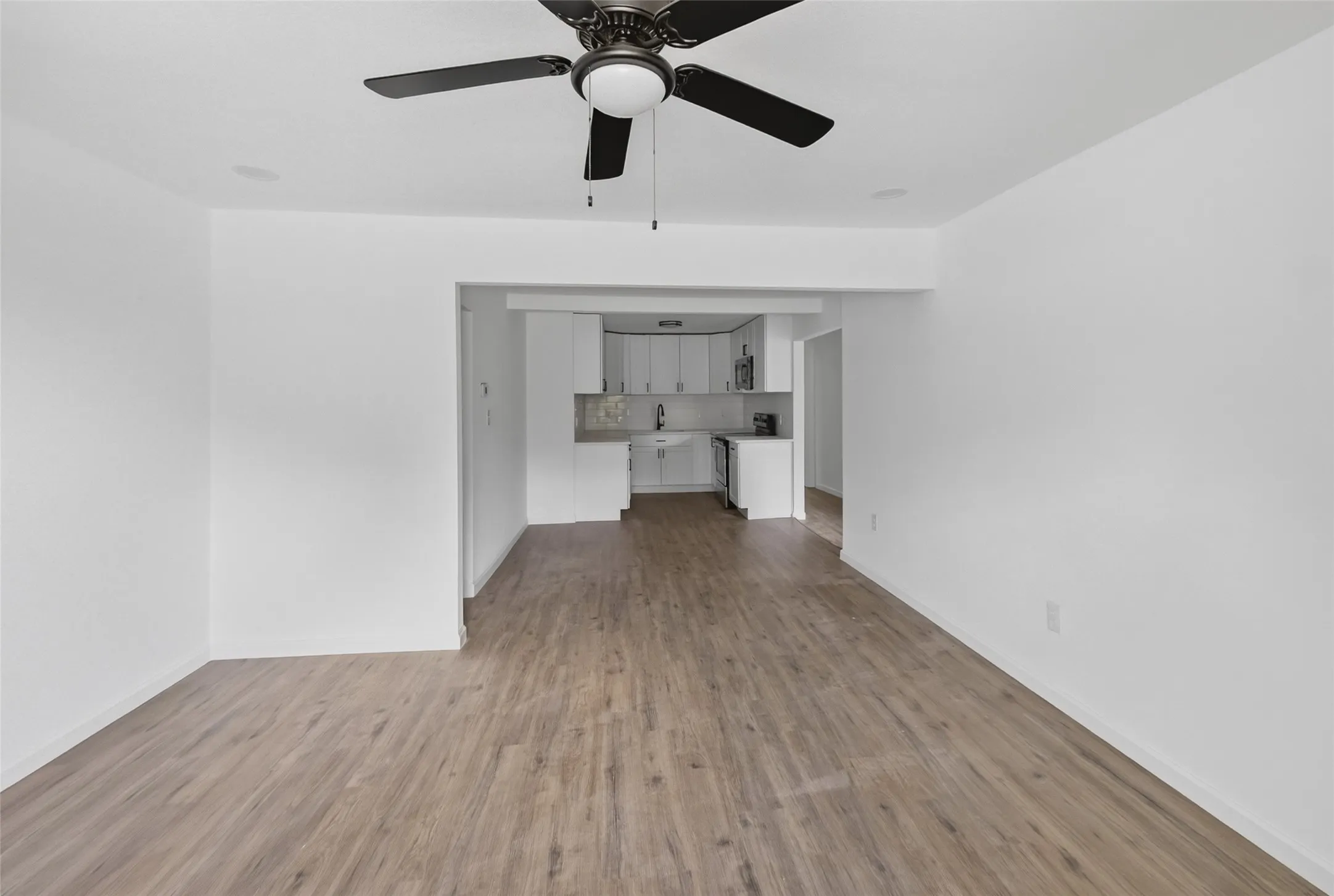 Open-concept living space featuring wood-finish flooring and a ceiling fan with integrated lighting