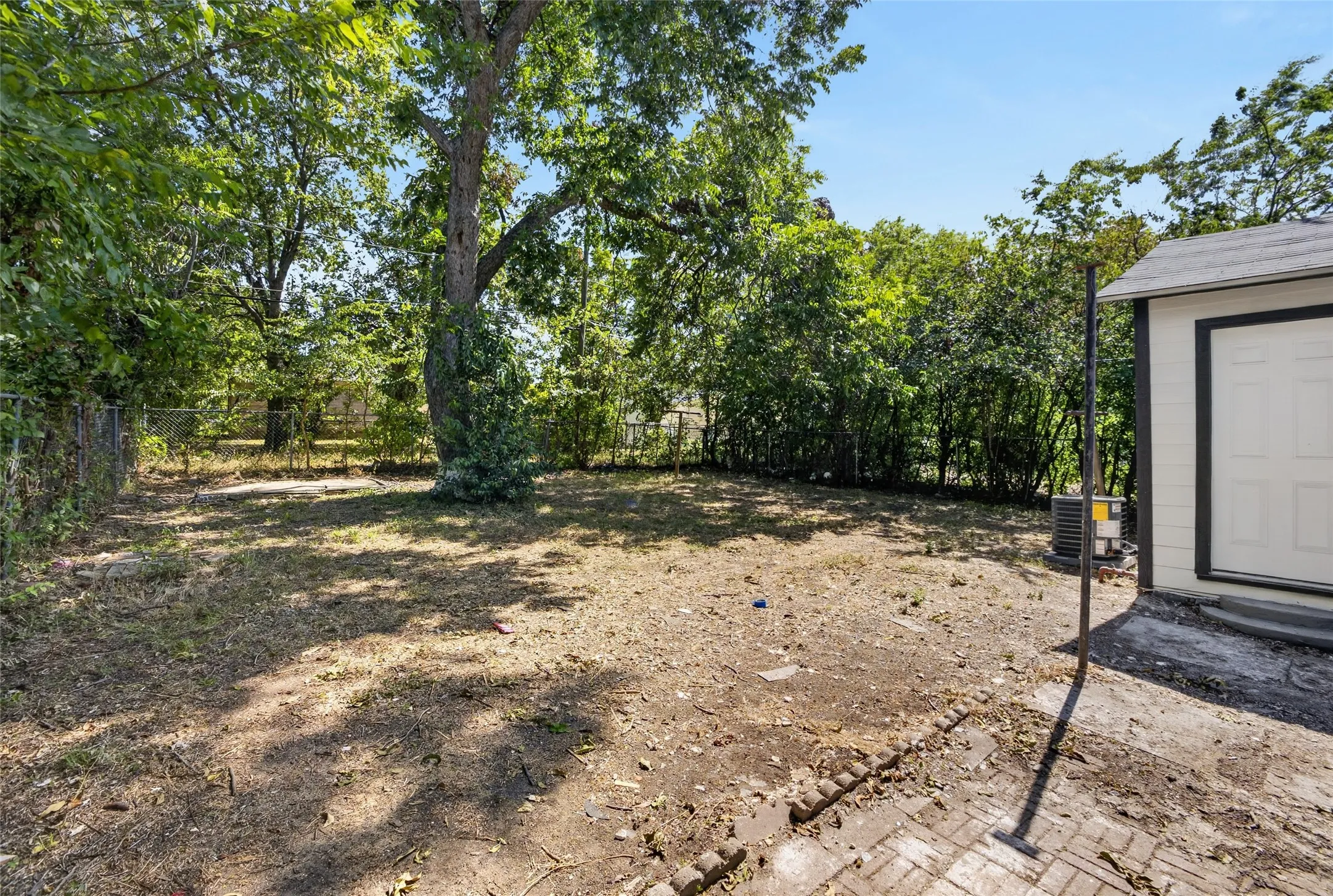 Expansive yard featuring mature trees and a chain-link fence