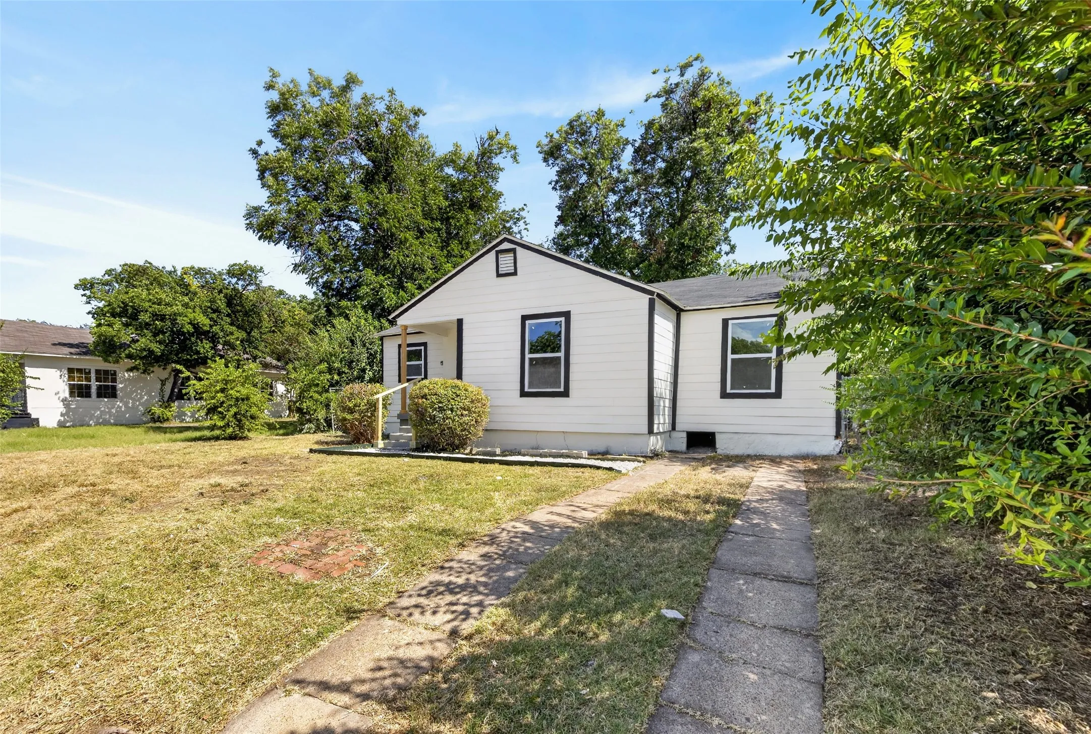 White siding exterior with contrasting dark trim, a covered front entry, and a concrete pathway