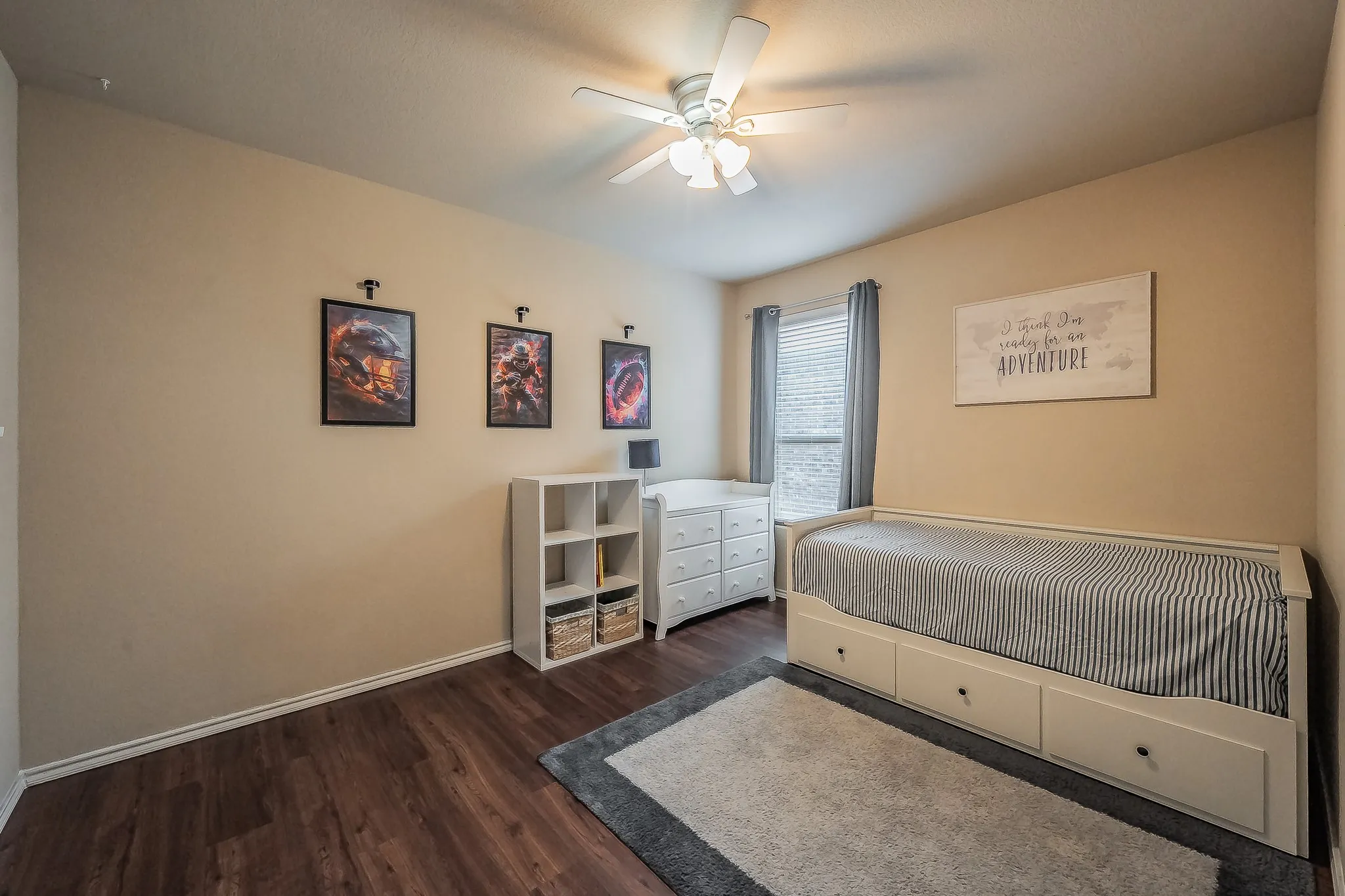 Room featuring wood-finish luxury vinyl flooring, a ceiling fan with integrated lighting, and a window with blinds and drapes