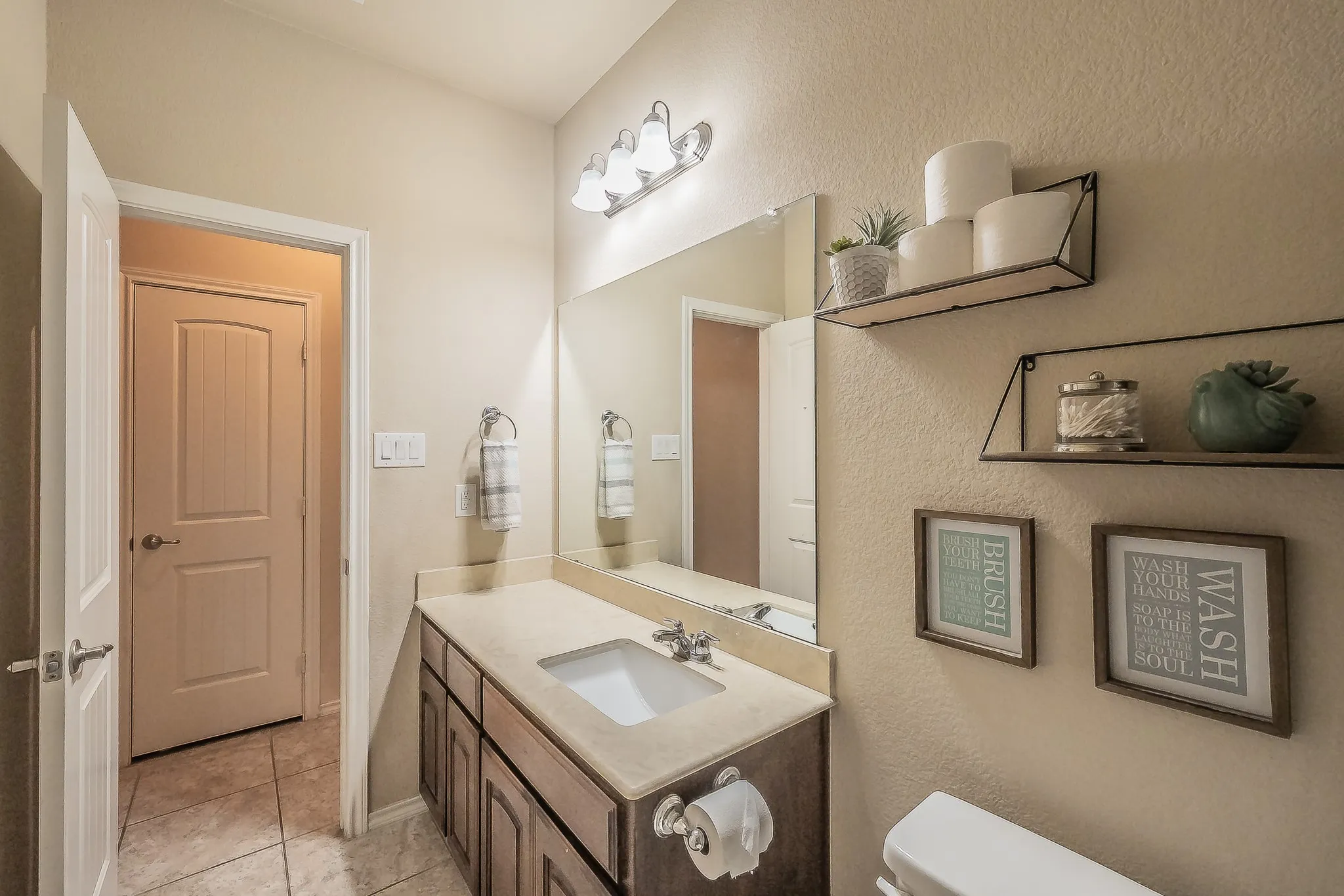 Bathroom vanity featuring a single basin sink set in a light-toned countertop