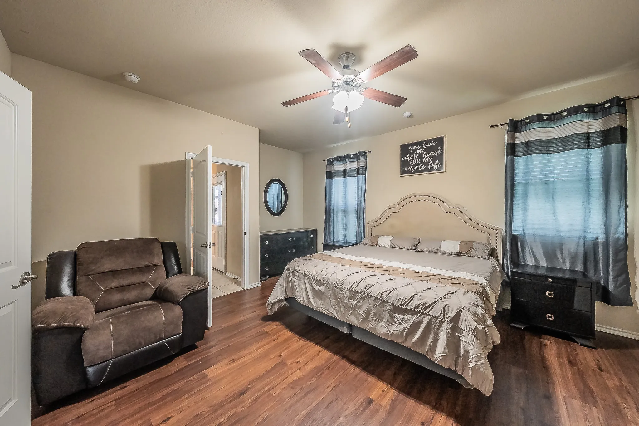 Spacious room featuring luxury vinyl wood- finish flooring, a ceiling fan with integrated lighting, and two windows with blinds