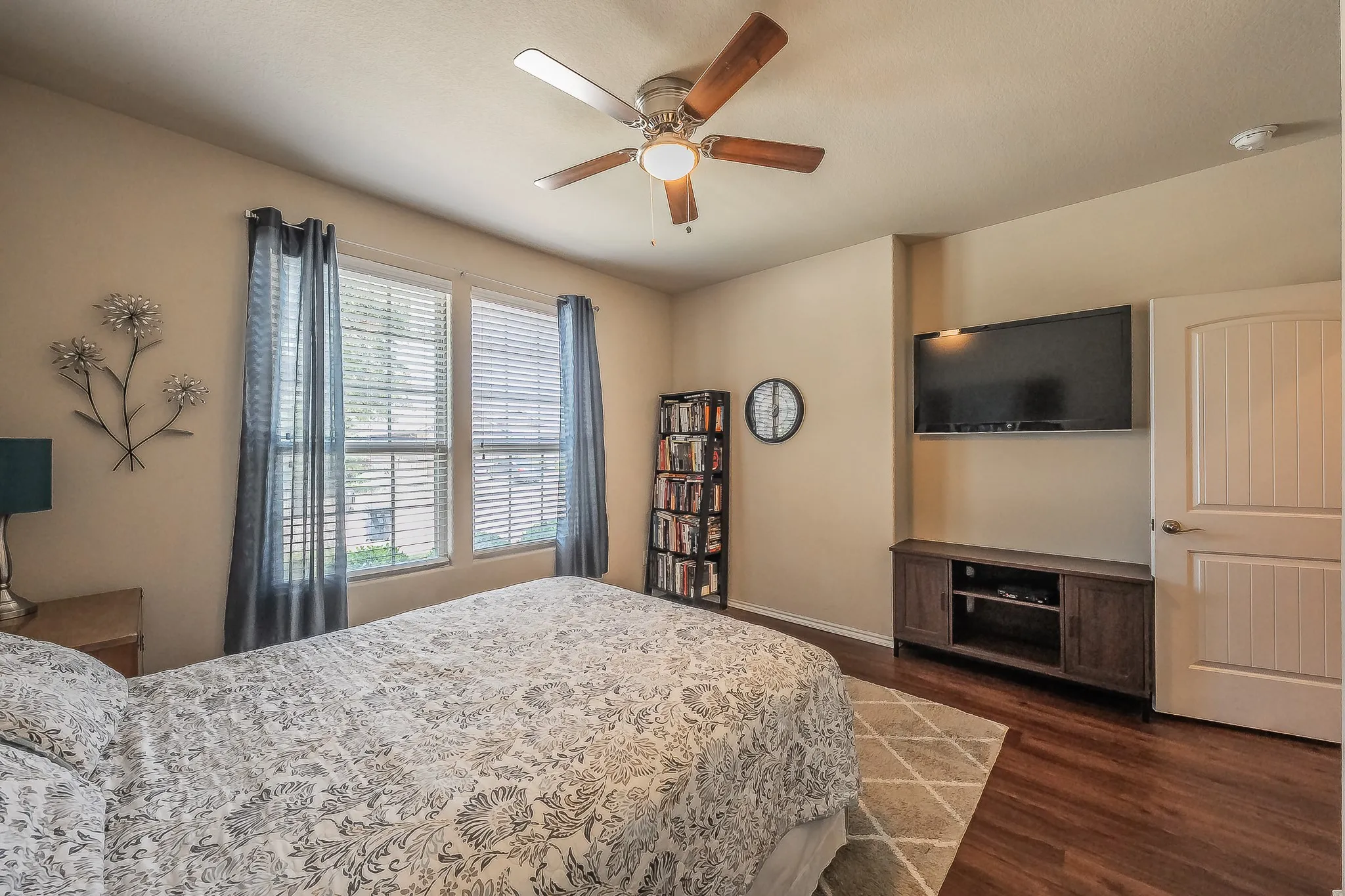 Interior room featuring wood-finish luxury vinyl flooring, a ceiling fan with light fixture, and two window openings