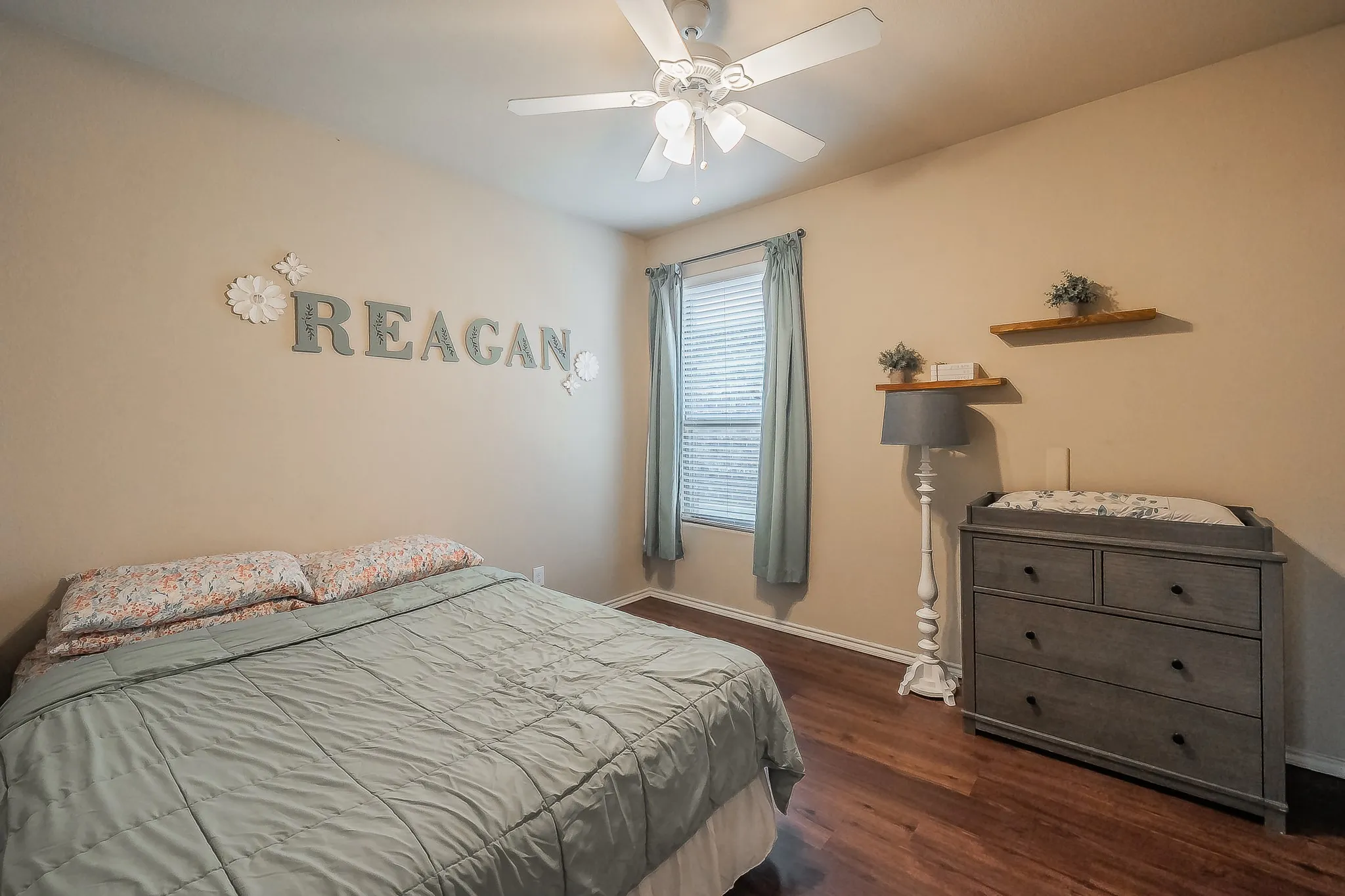 Bedroom featuring wood-finish  luxury vinyl flooring, a ceiling fan, and a window with blinds offering natural light,