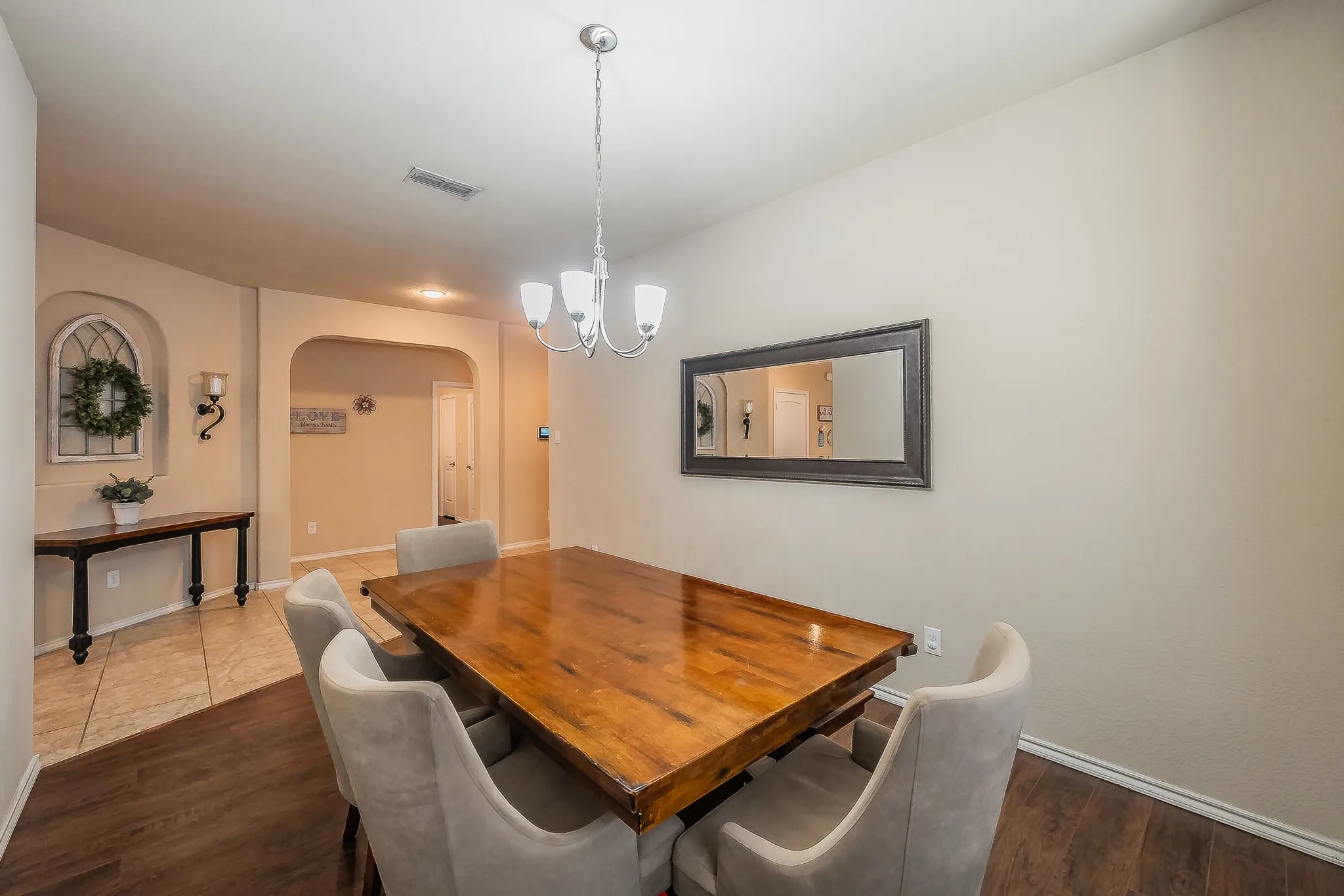 Dining space featuring luxury vinyl flooring, a contemporary chandelier, and an arched entry