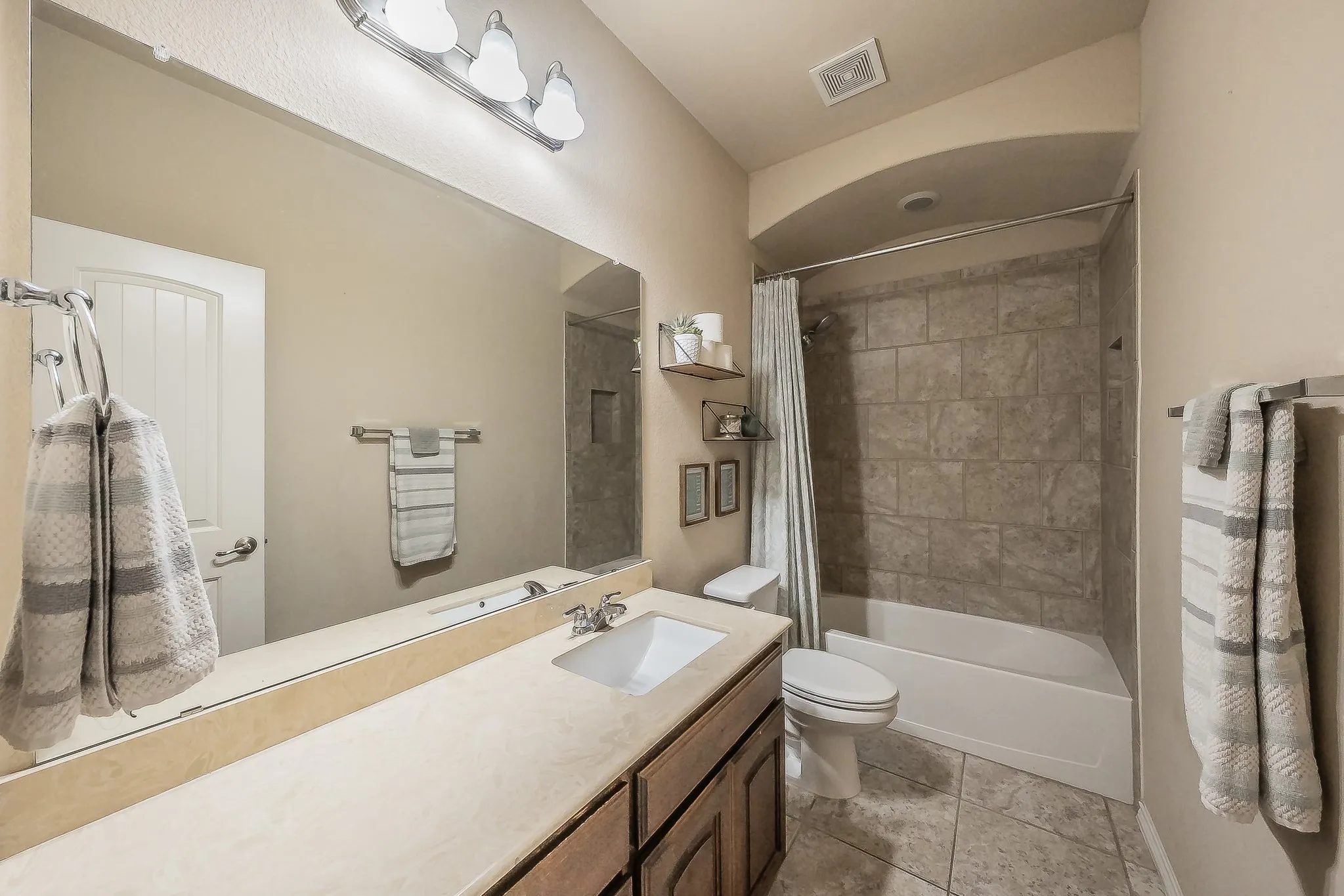 Bathroom featuring a single vanity with a solid surface granite countertop, integrated sink, and wood-finish cabinetry