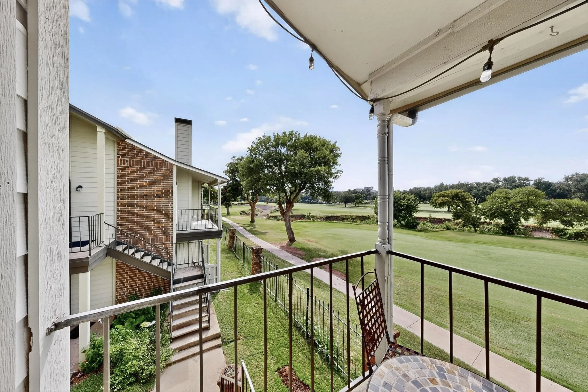 Balcony featuring black metal railings and overhead string lighting