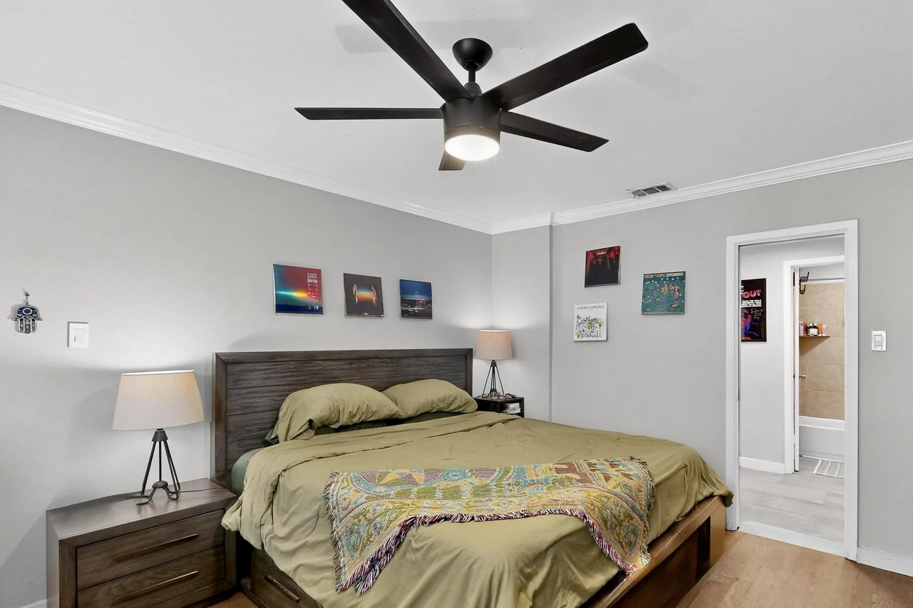 Spacious room featuring wood-finish flooring, a contemporary ceiling fan with integrated lighting, crown molding, and light gray walls