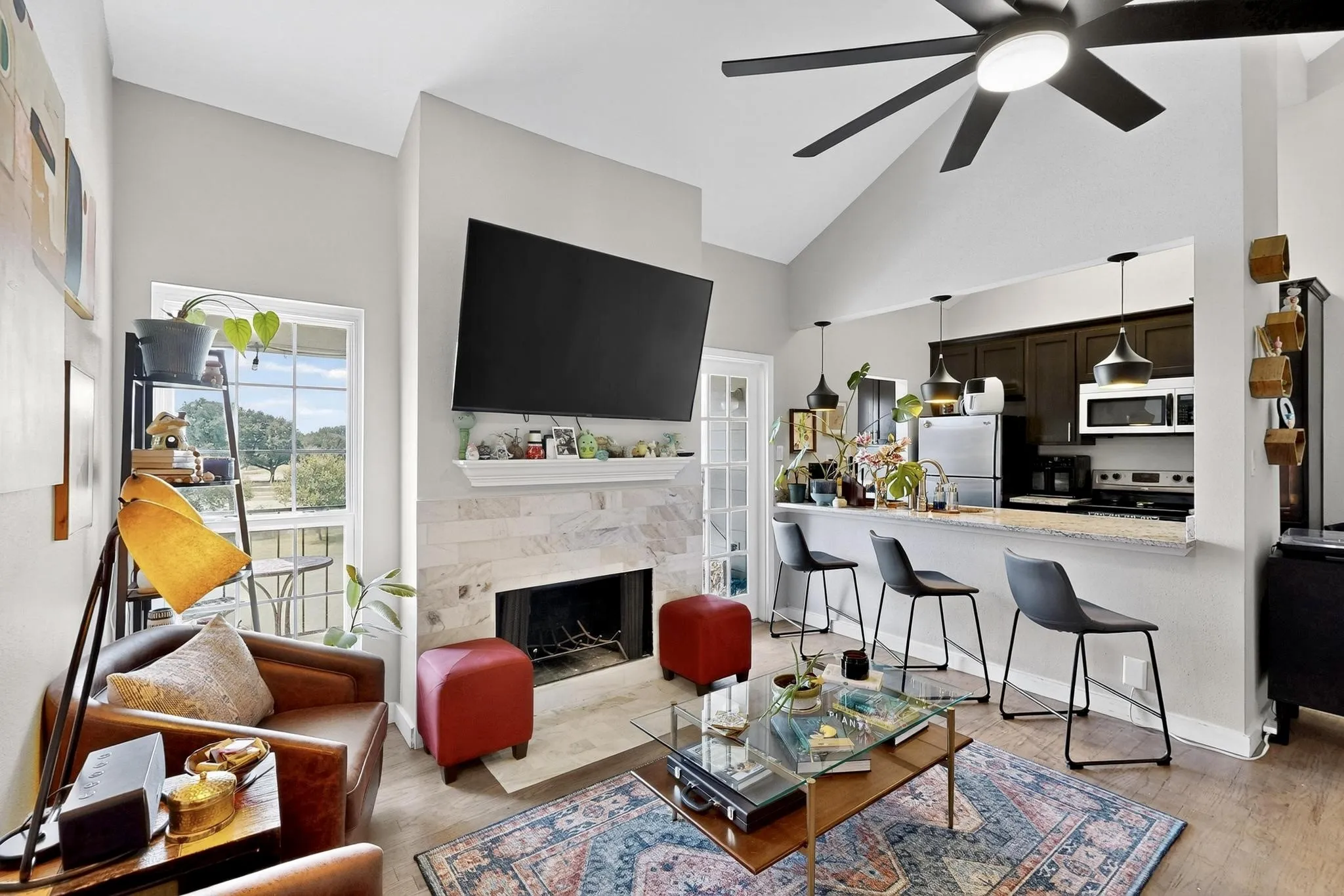 Living area featuring vaulted ceilings, a fireplace with a stone surround and mantel, and wood-finish flooring