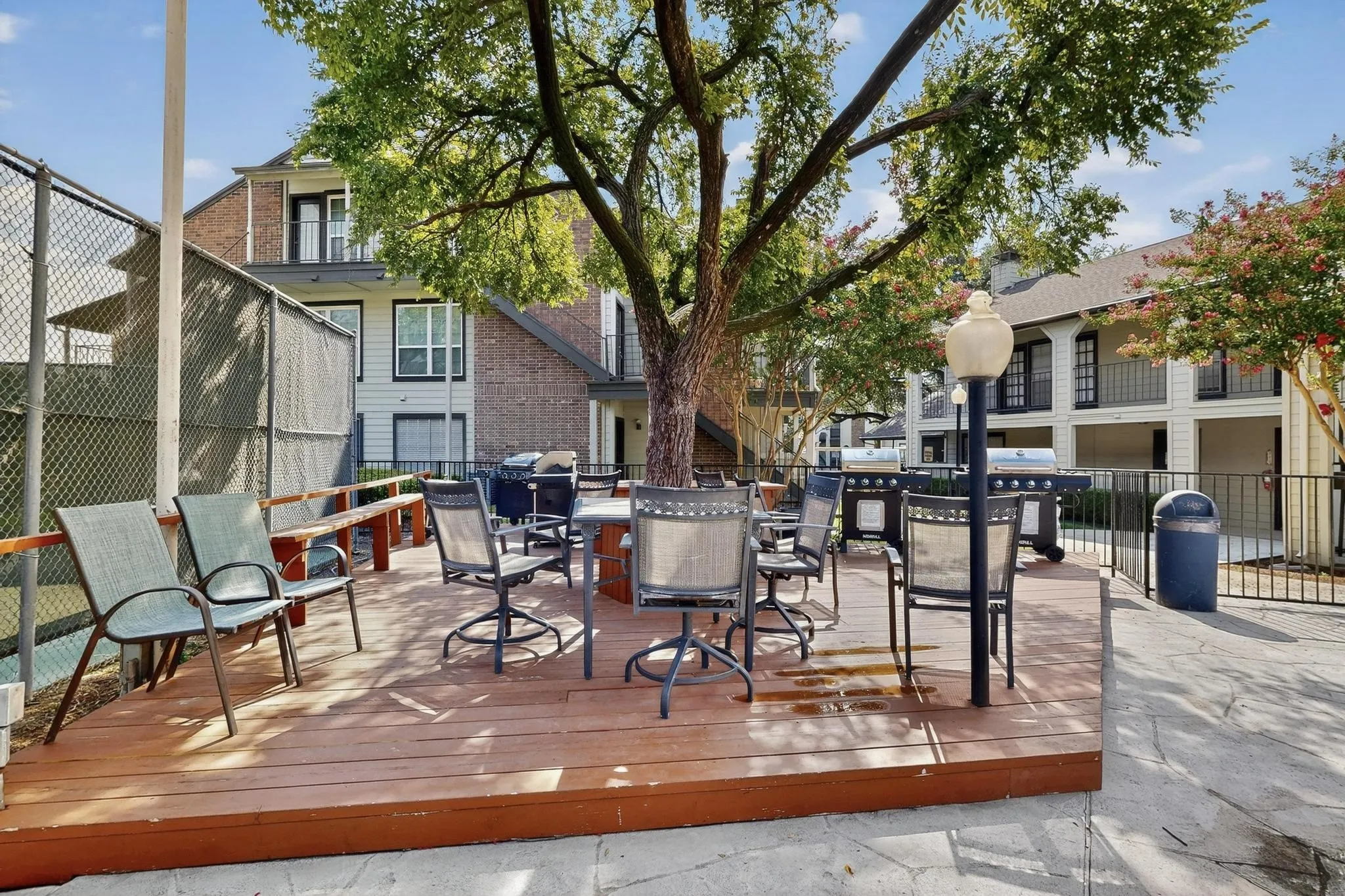 Expansive outdoor wood-finish decking featuring a built-in bench, surrounding a mature shade tree