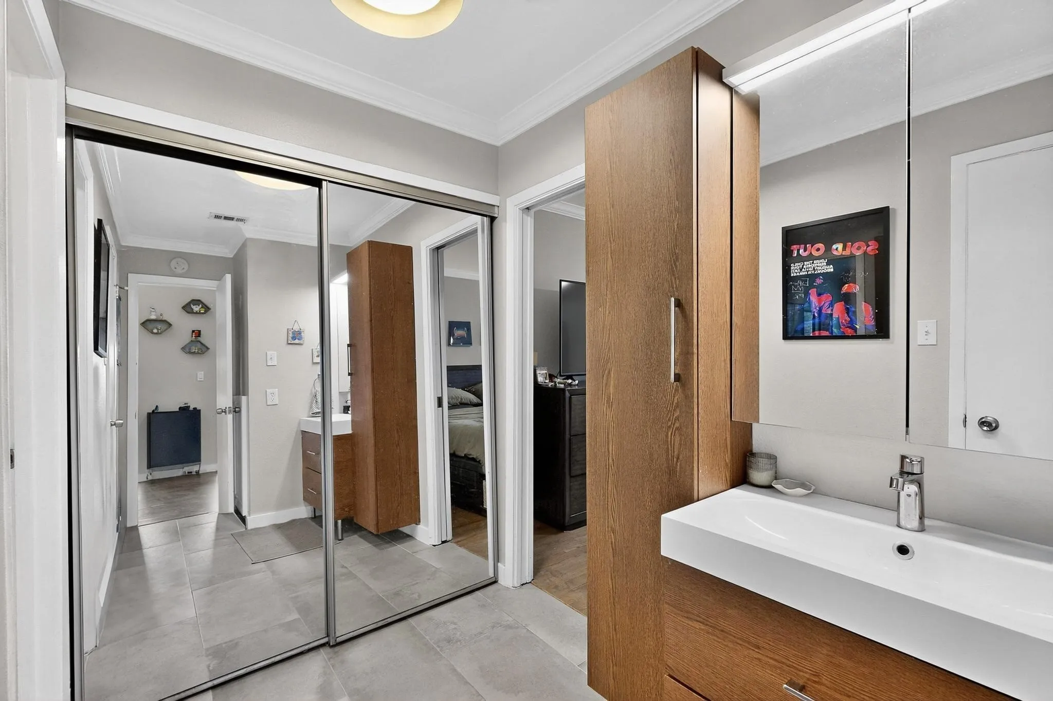 Bathroom featuring a modern floating vanity with an integrated white sink, chrome faucet, and a large wall-mounted mirror with integrated lighting