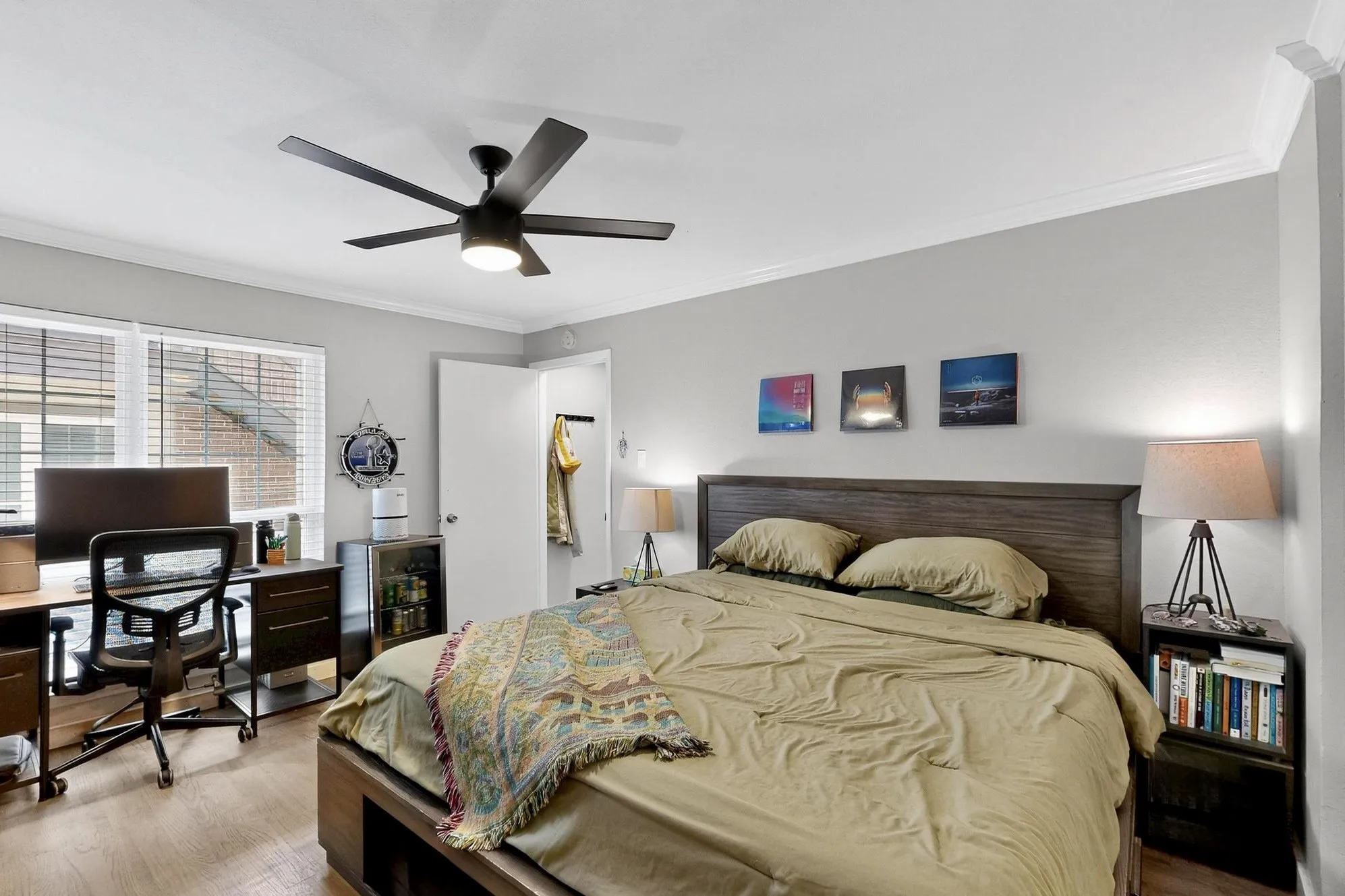 Bedroom featuring wood-finish flooring, a contemporary ceiling fan, crown molding, and a built-in desk area with integrated drawers