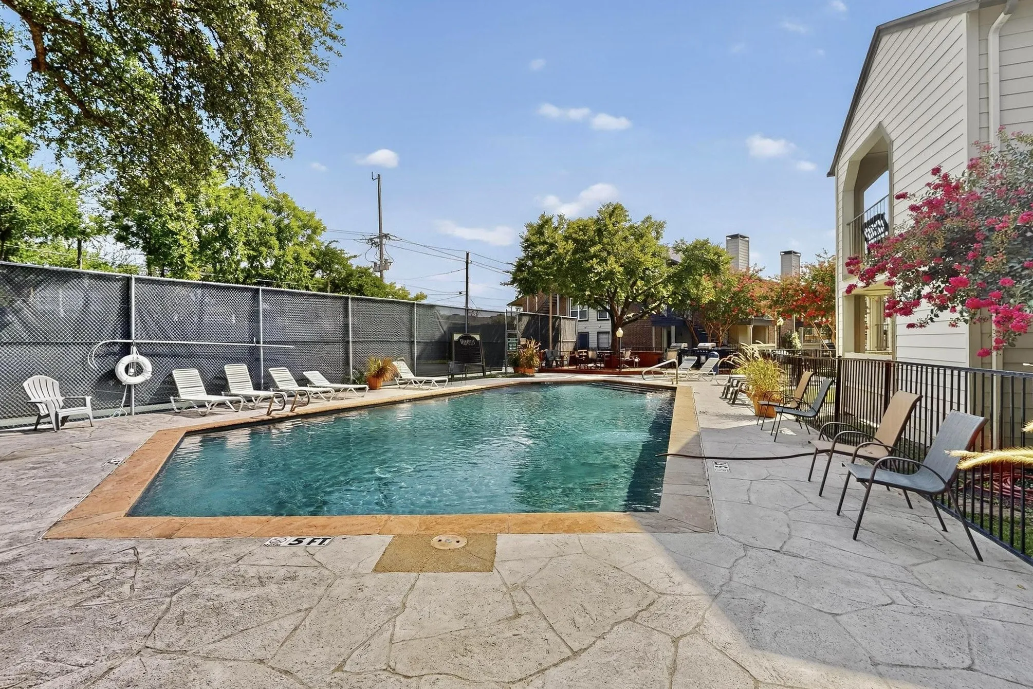 Swimming pool featuring a textured concrete deck and perimeter fencing