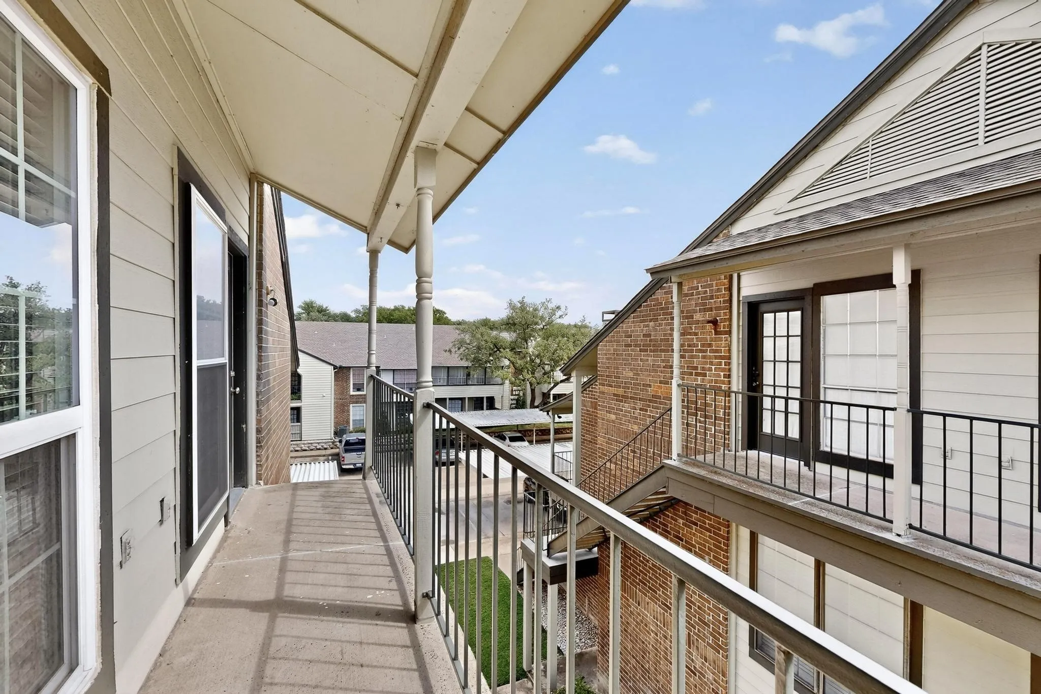Private balcony featuring concrete flooring, a decorative metal railing, and a covered ceiling