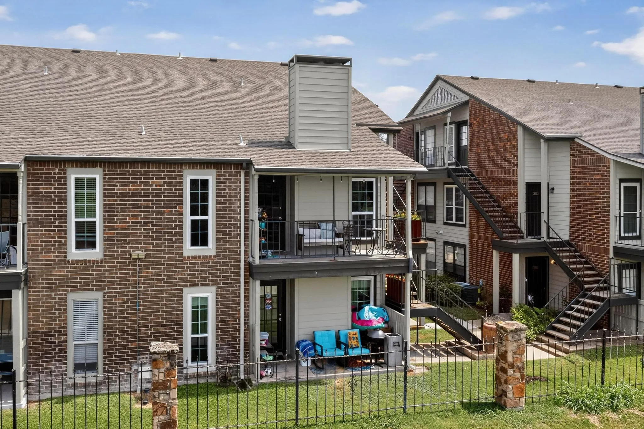 Exterior brick and siding construction featuring a private balcony and ground-level patio