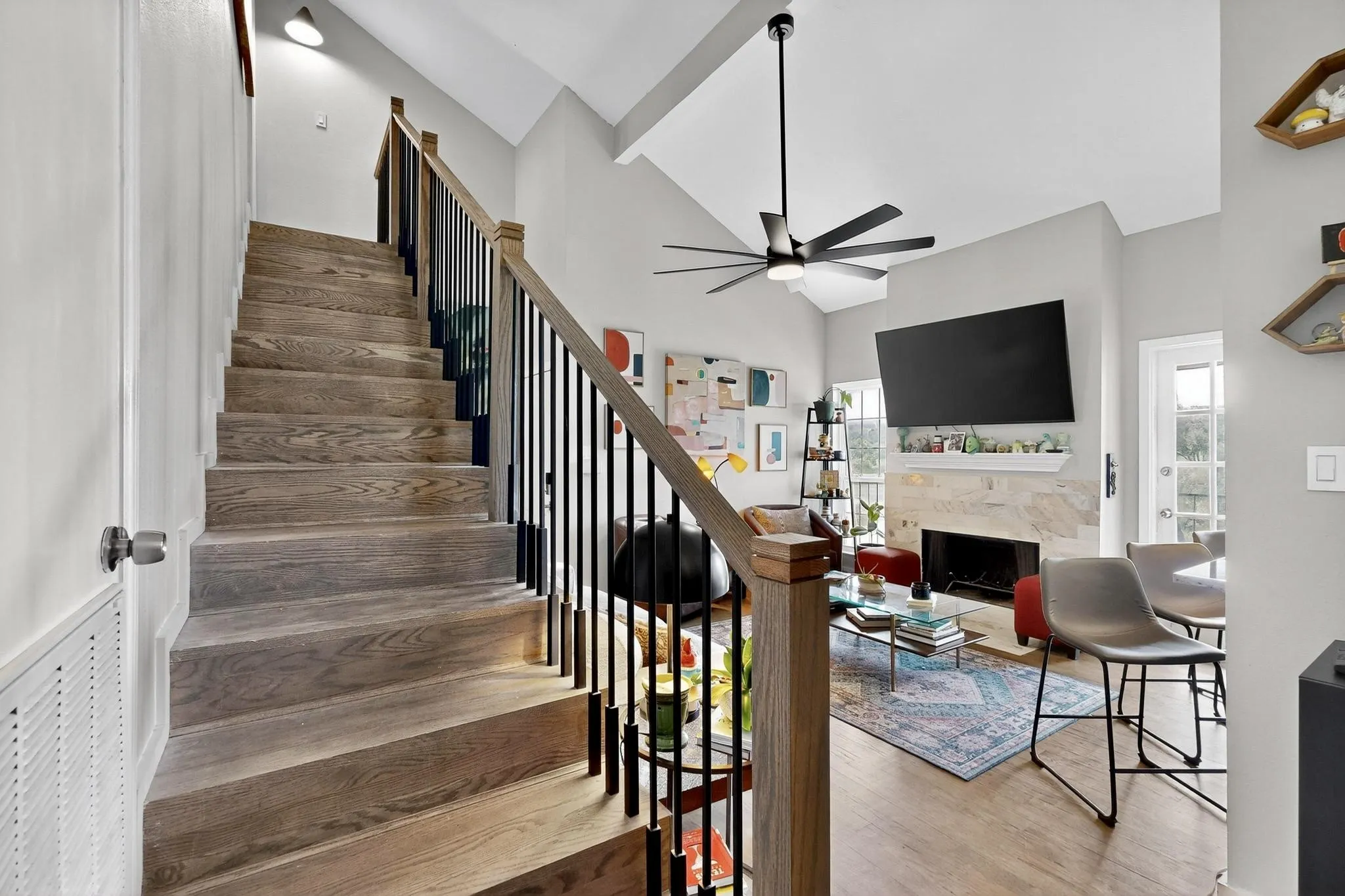 Wood-finish staircase with black metal balusters and wood handrail