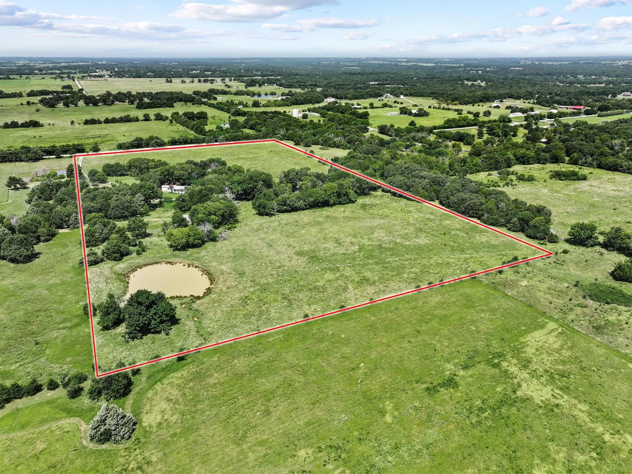 Acreage featuring a natural pond, mature trees, and open grassy areas