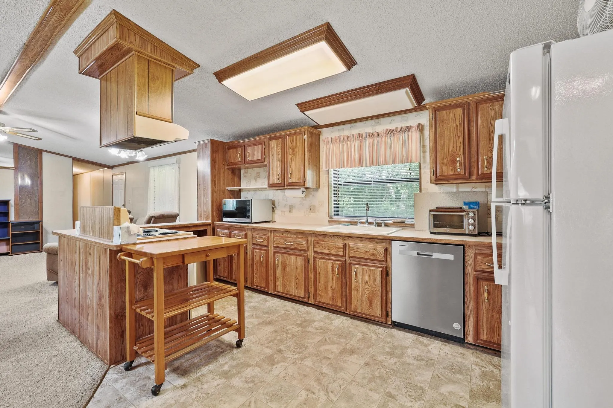 Kitchen featuring wood-finish cabinetry, built-in dishwasher, ample counter space