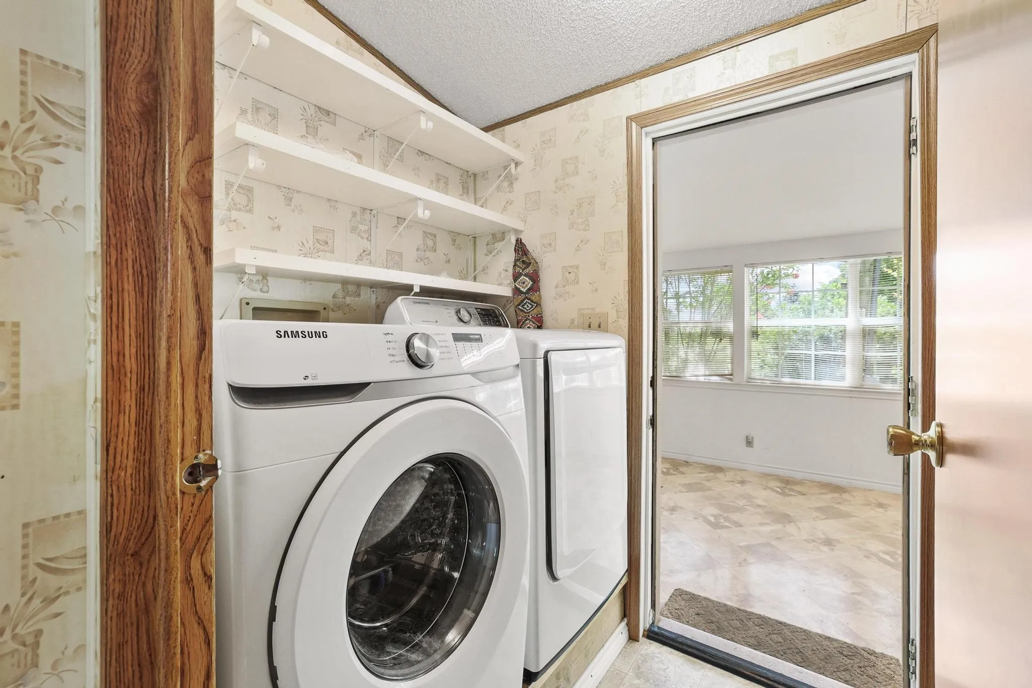 Dedicated laundry area featuring white front-load appliances and wall-mounted shelving