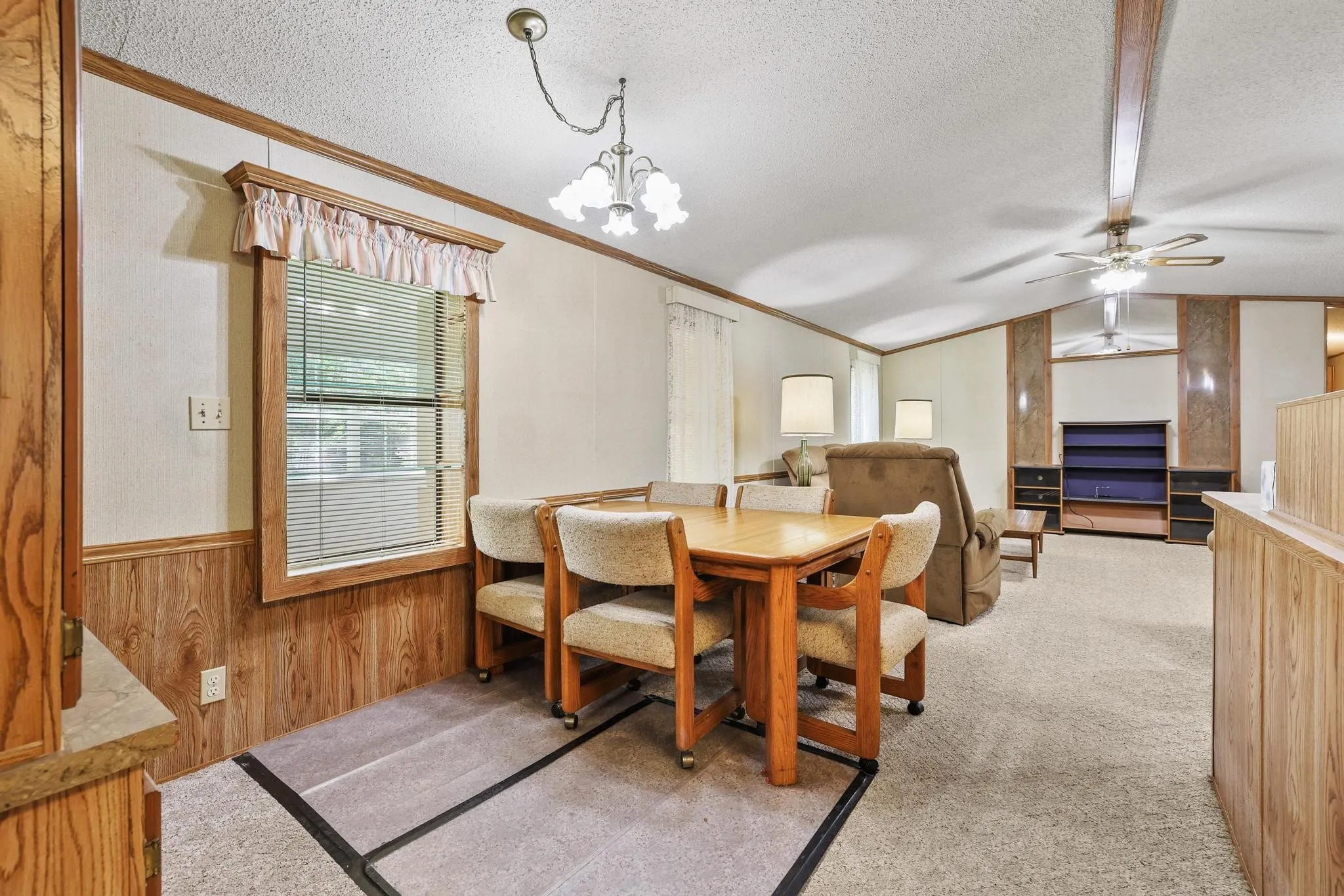 Dining area with wood-finish wainscoting and trim, featuring a window with blinds