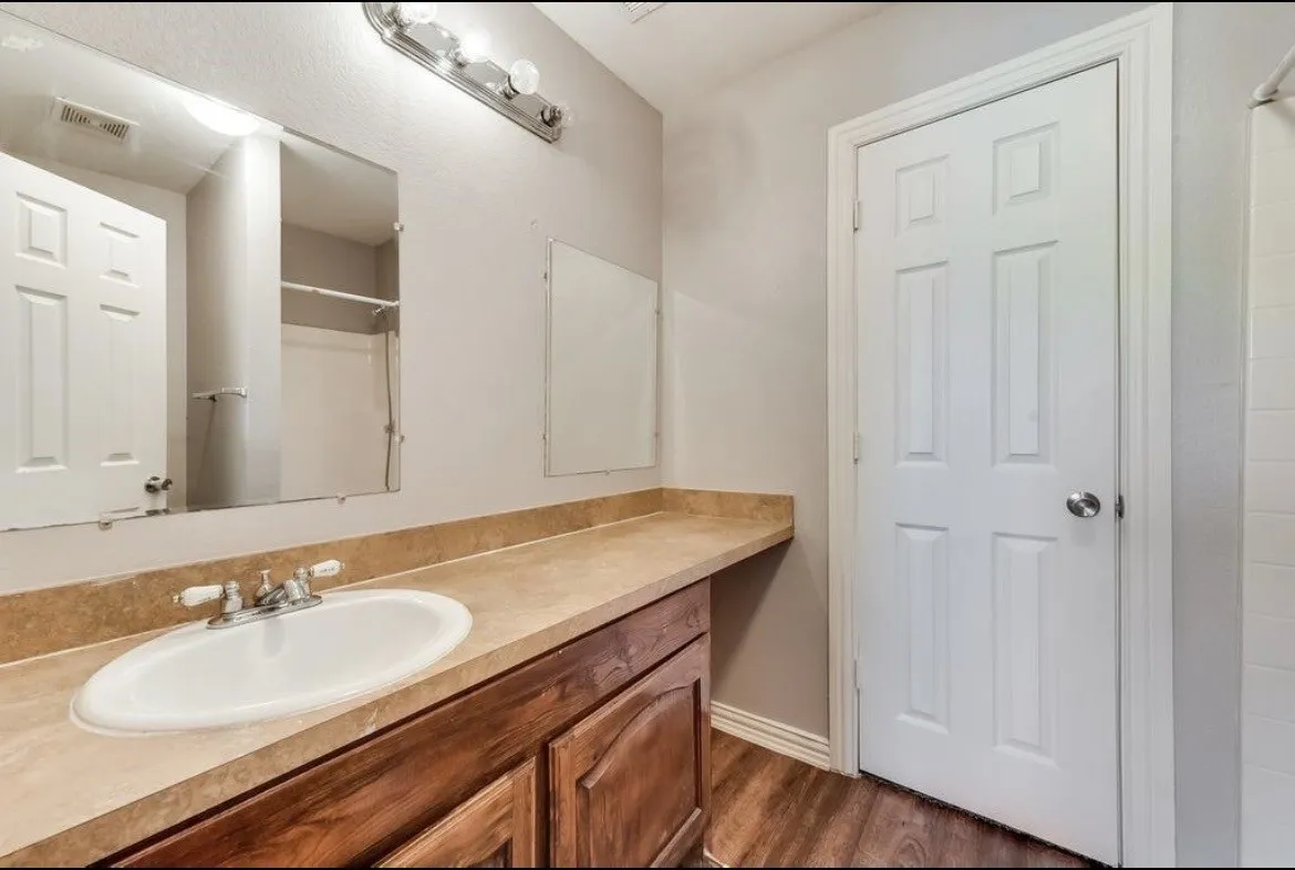 Bathroom vanity featuring a single basin, dual-handle faucet, and an expansive countertop