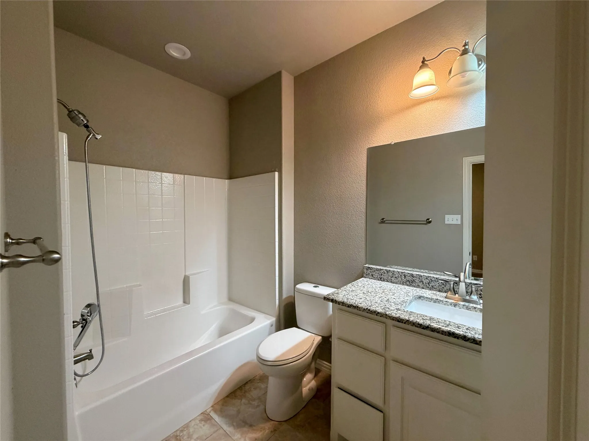 Bathroom featuring a white tub/shower combination, a vanity with a white cabinet, a speckled countertop, and a mirror