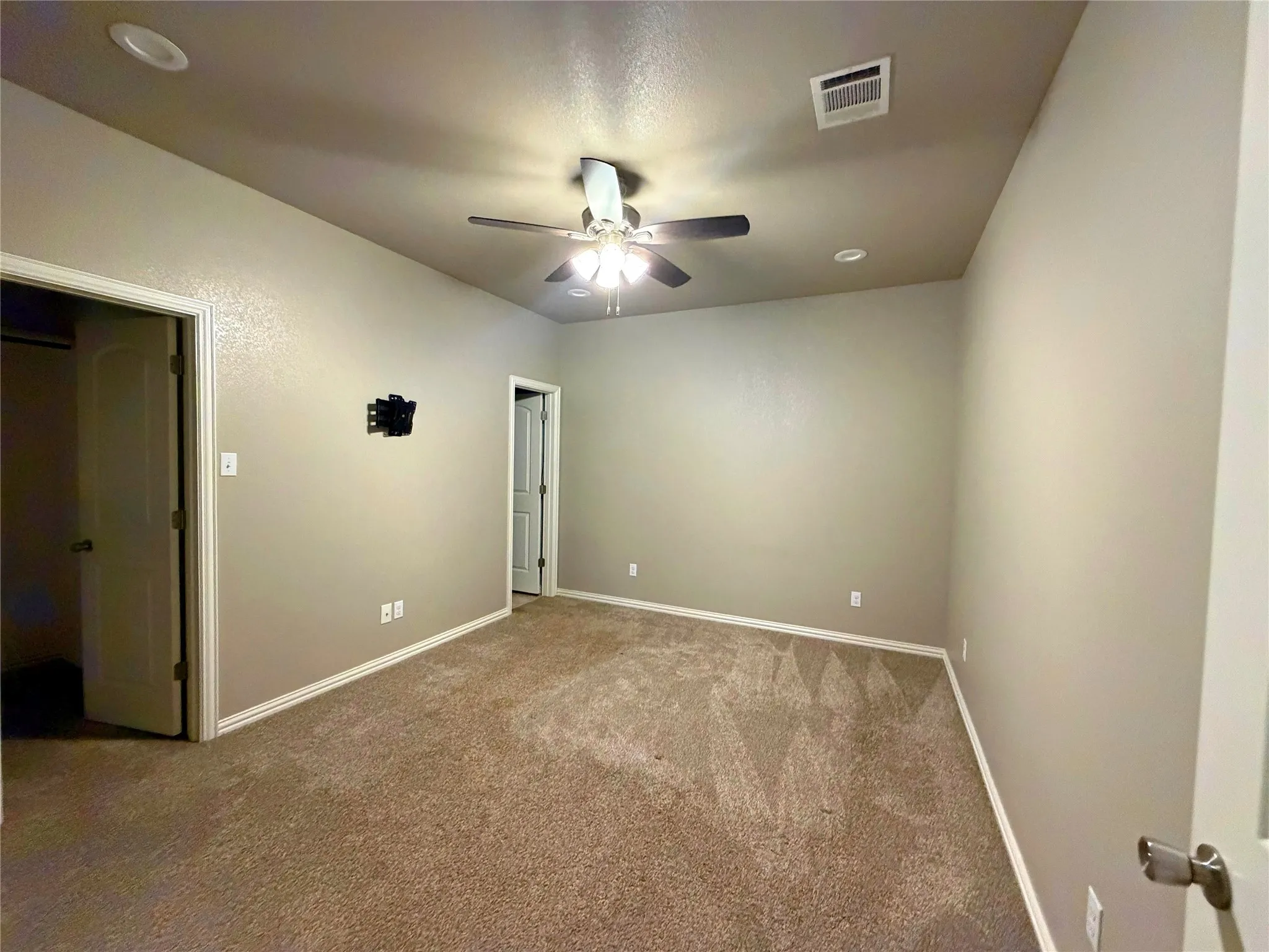 Carpeted interior space featuring light neutral wall paint, white trim, recessed lighting, and a ceiling fan with integrated light fixture