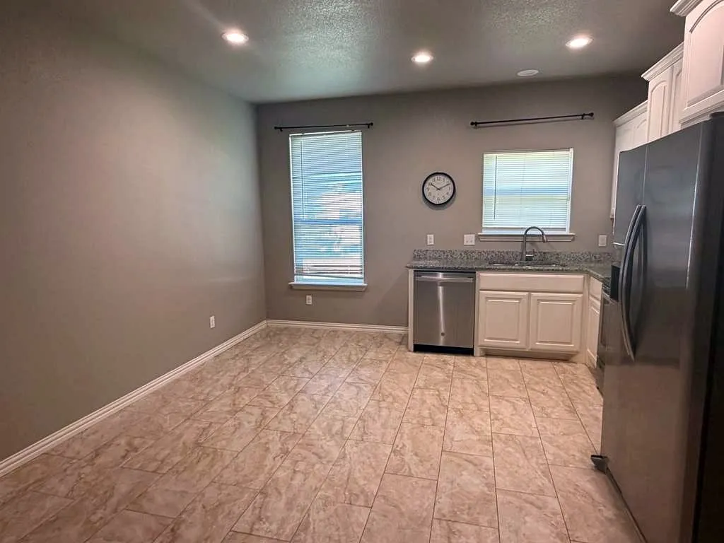 Kitchen space featuring tile flooring, recessed lighting, white cabinetry, granite countertops, and stainless steel appliances