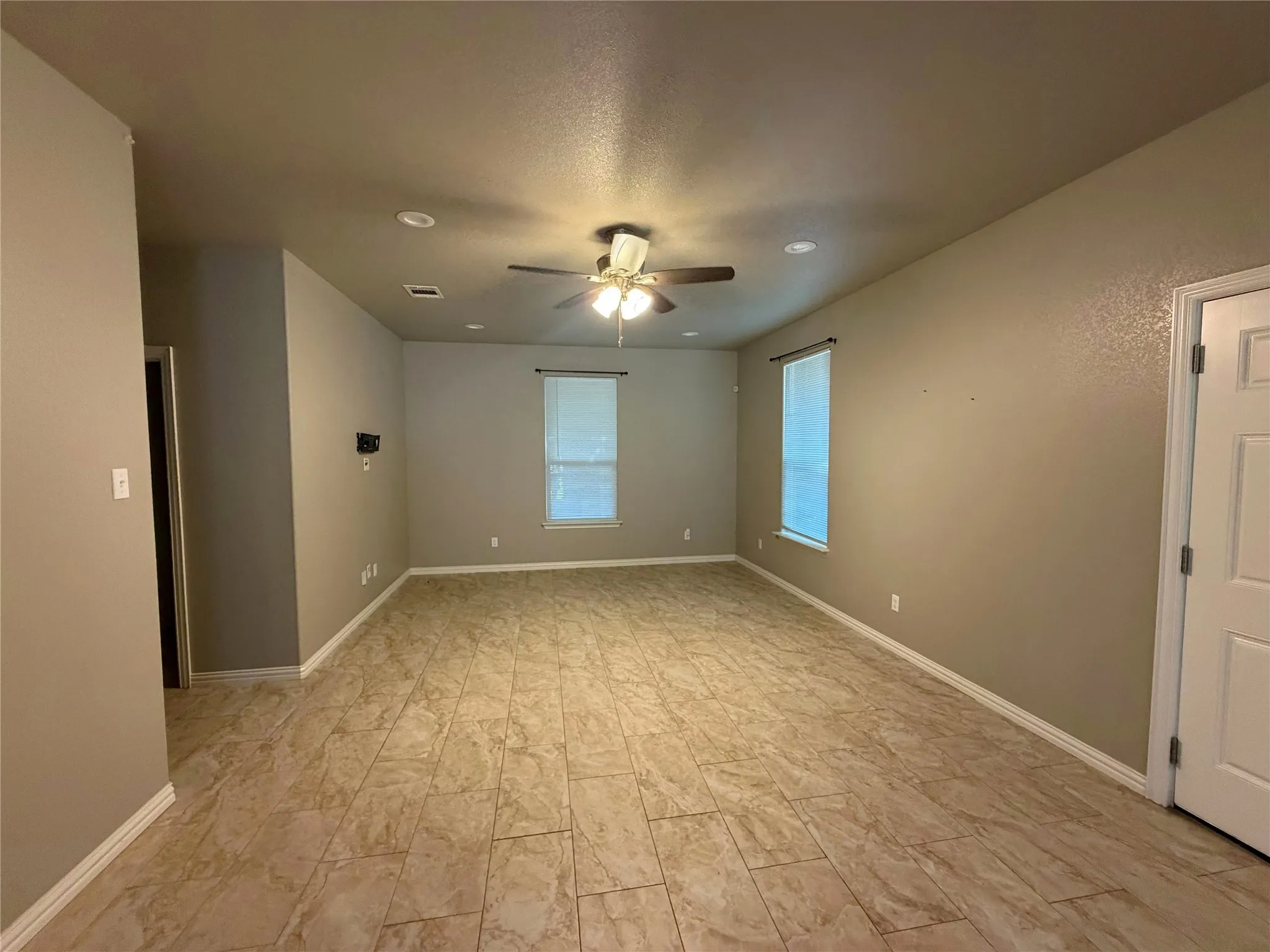 Spacious living area featuring large format tile flooring, recessed lighting, and a ceiling fan