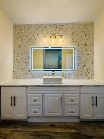 Vanity featuring white shaker-style cabinetry with matte black hardware, a rectangular vessel sink, and a quartz countertop