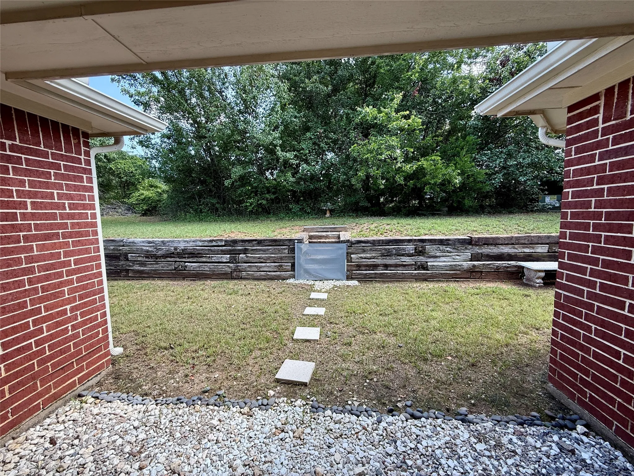 Expansive backyard featuring a tiered landscaping design with a wood retaining wall