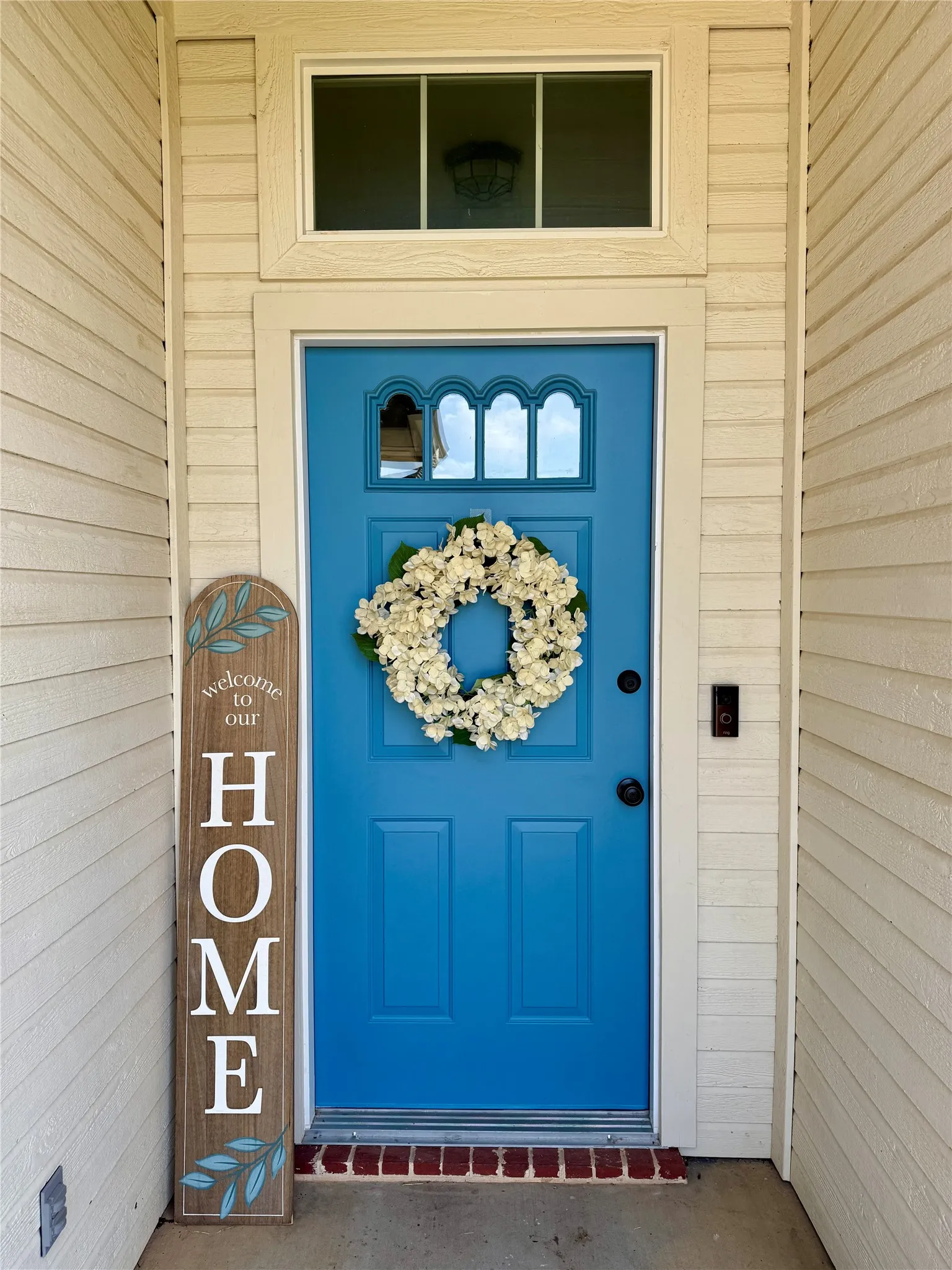 Vibrant blue entry door with decorative upper glass paneling and transom window