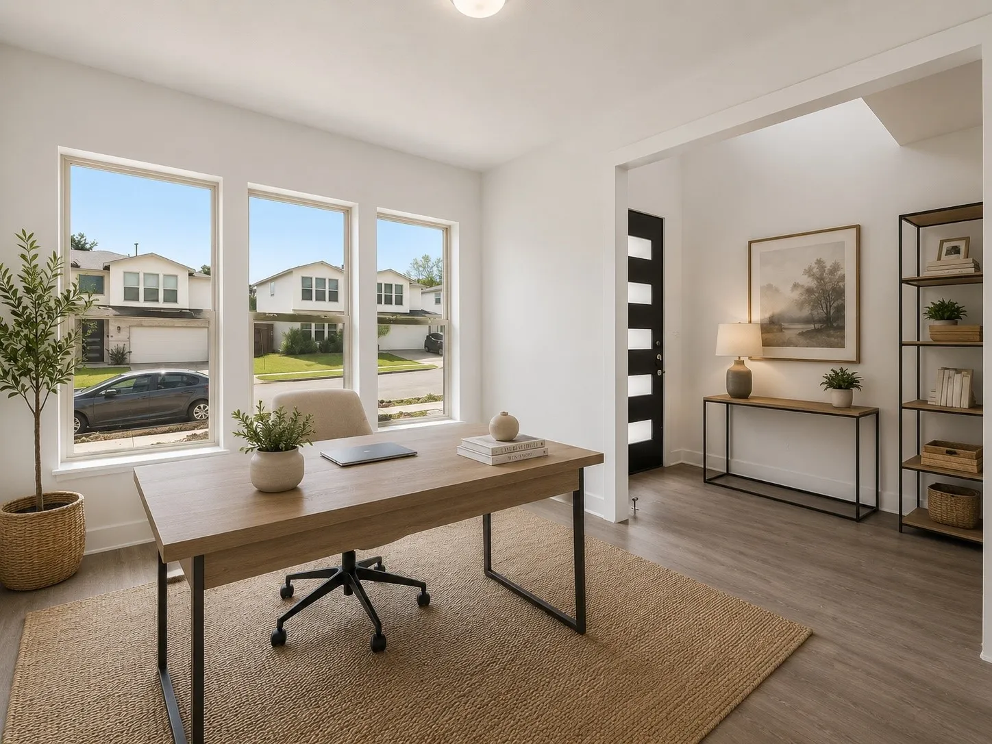 Bright interior room with three large windows, wood-finish flooring, and a modern black entry door with frosted glass panels