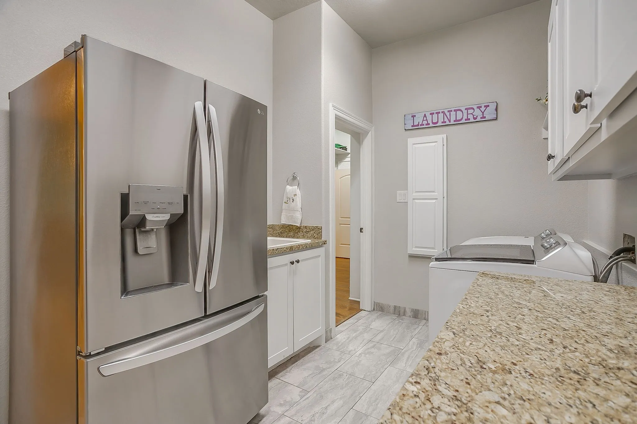 Utility room with space for refrigerator and cabinets for additional storage with sink