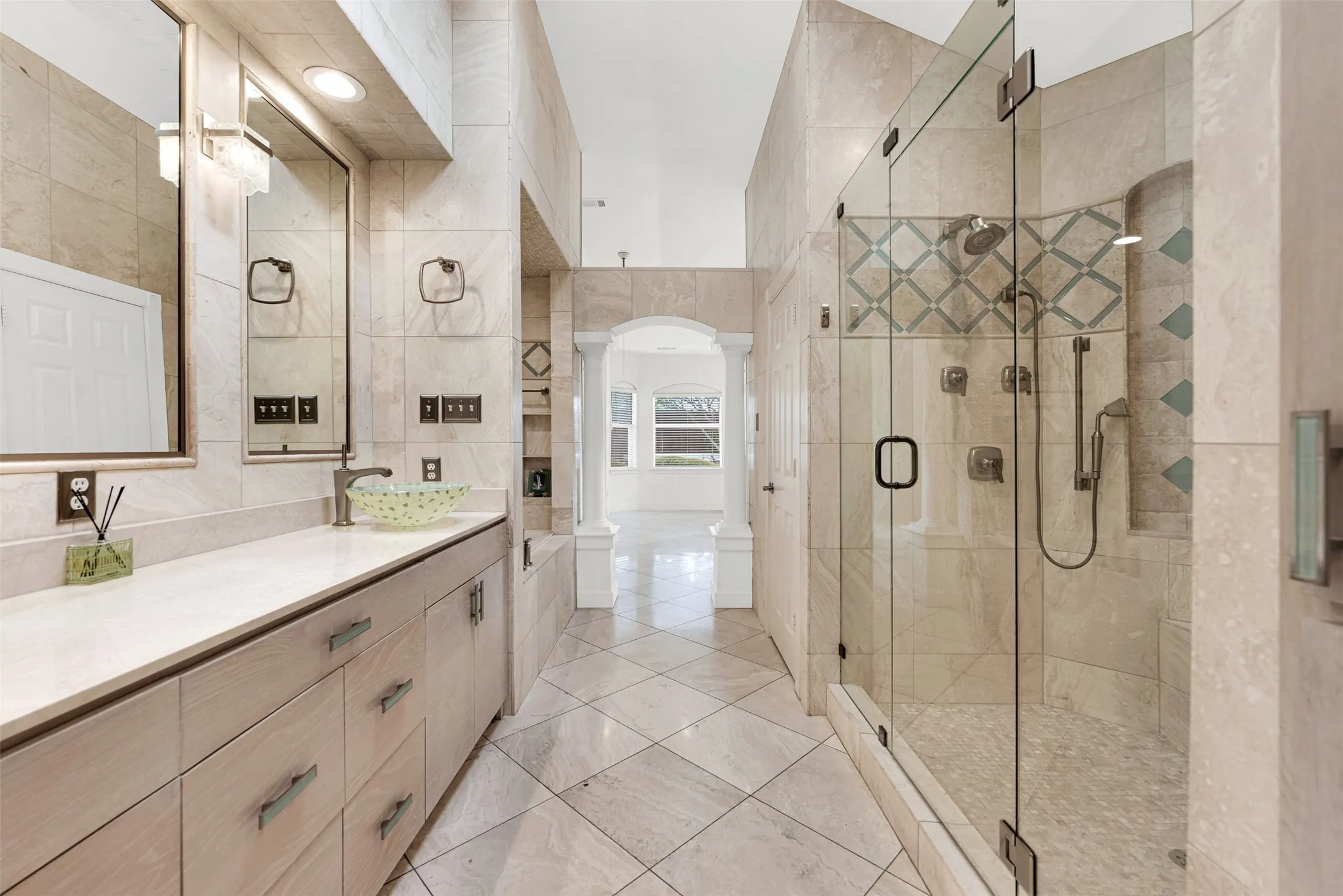 Seamless glass panels keep the sightlines open, blending the walk-in shower with the polished vanity area. Step onto the smooth, cool tiles wrapped in a plush robe to begin a slow, pampering weekend self-care ritual.