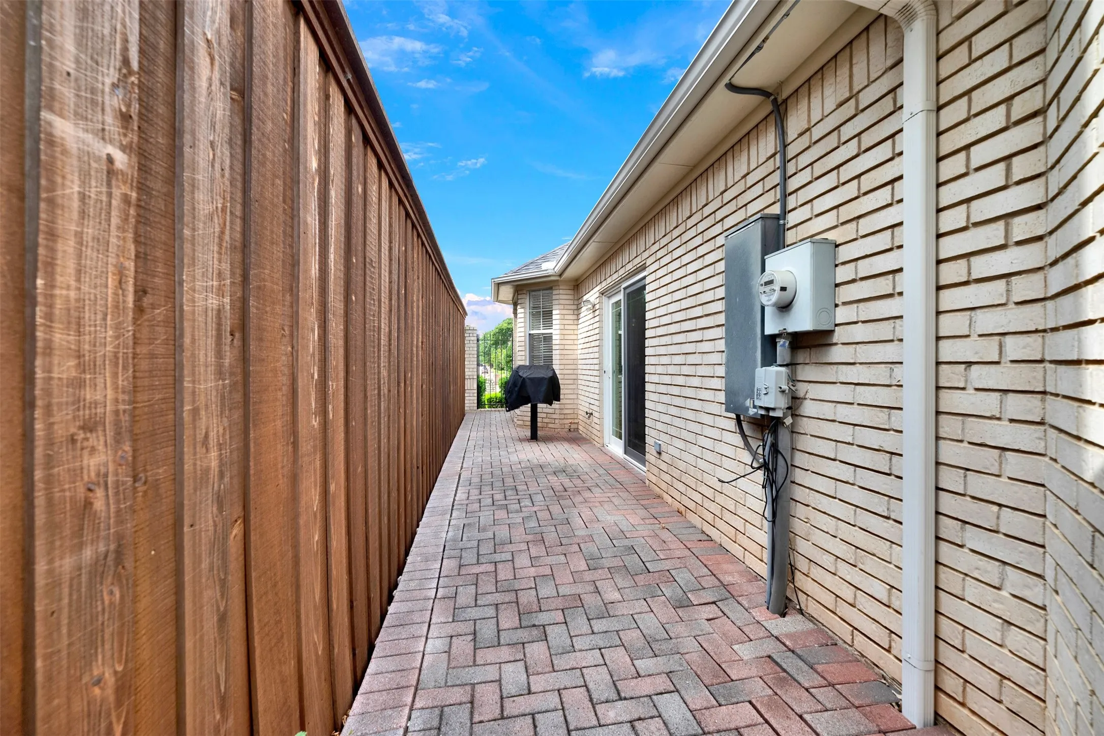 A sleek sliding glass door opens onto a long, structured pathway, seamlessly connecting the indoors with the fresh air. Visualize carrying your favorite morning coffee out this side entrance to greet a quiet, sunny dawn.