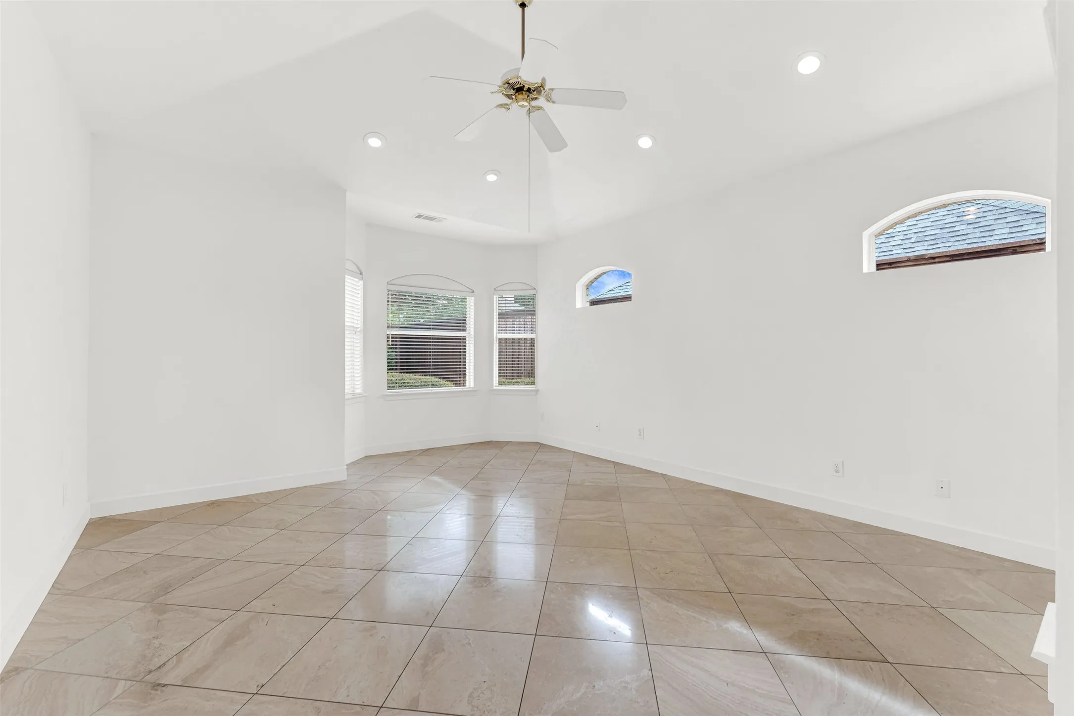 High-set, arched clerestory windows work alongside a bay alcove to wash the room in soft, balanced light. Wake up naturally as morning sunbeams slowly dance across the expansive polished tile floor.