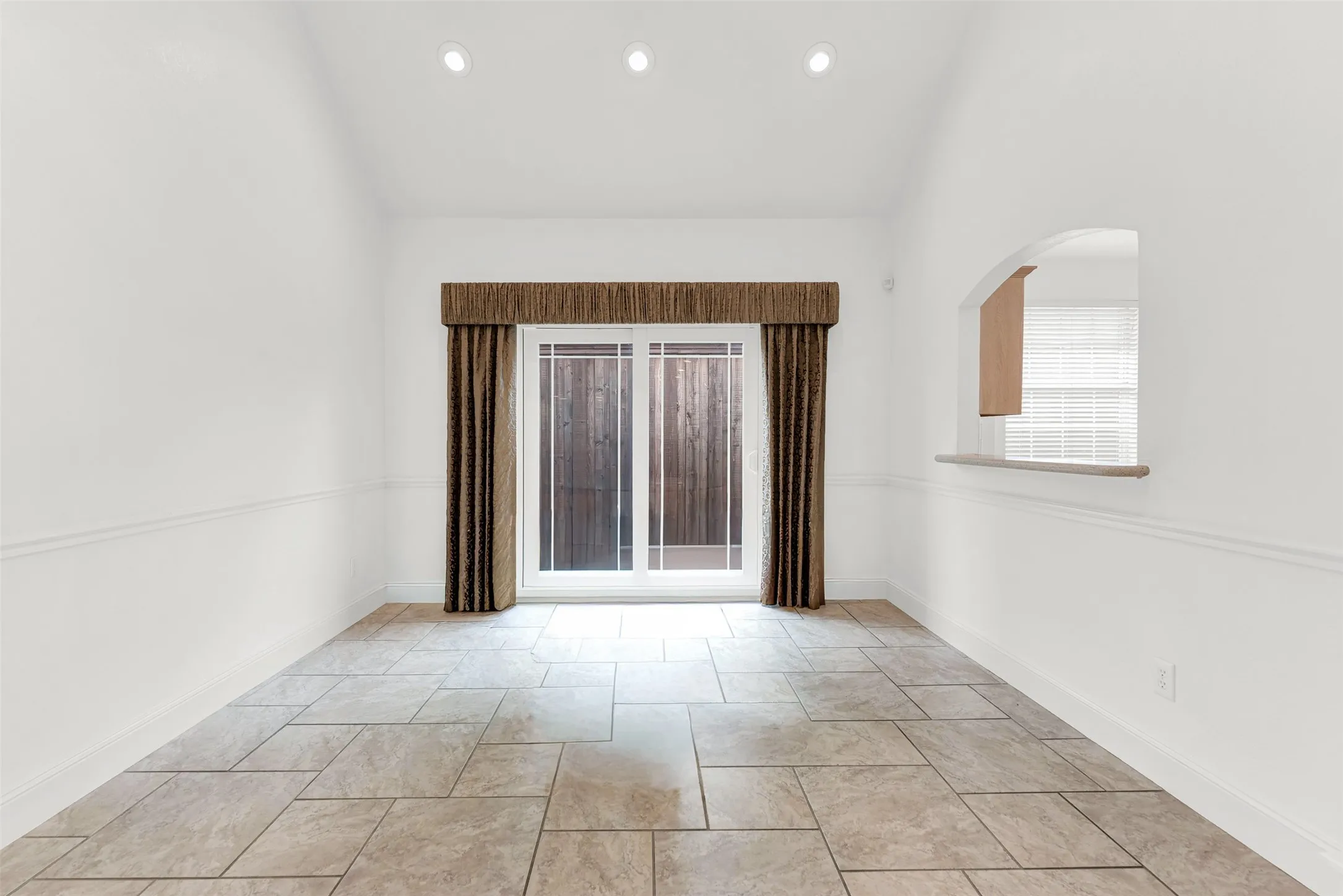 Soaring vaulted ceilings paired with floor-to-ceiling sliding glass doors create a bright, airy sanctuary. Visualize sitting down to a peaceful weekend breakfast illuminated by soft natural light