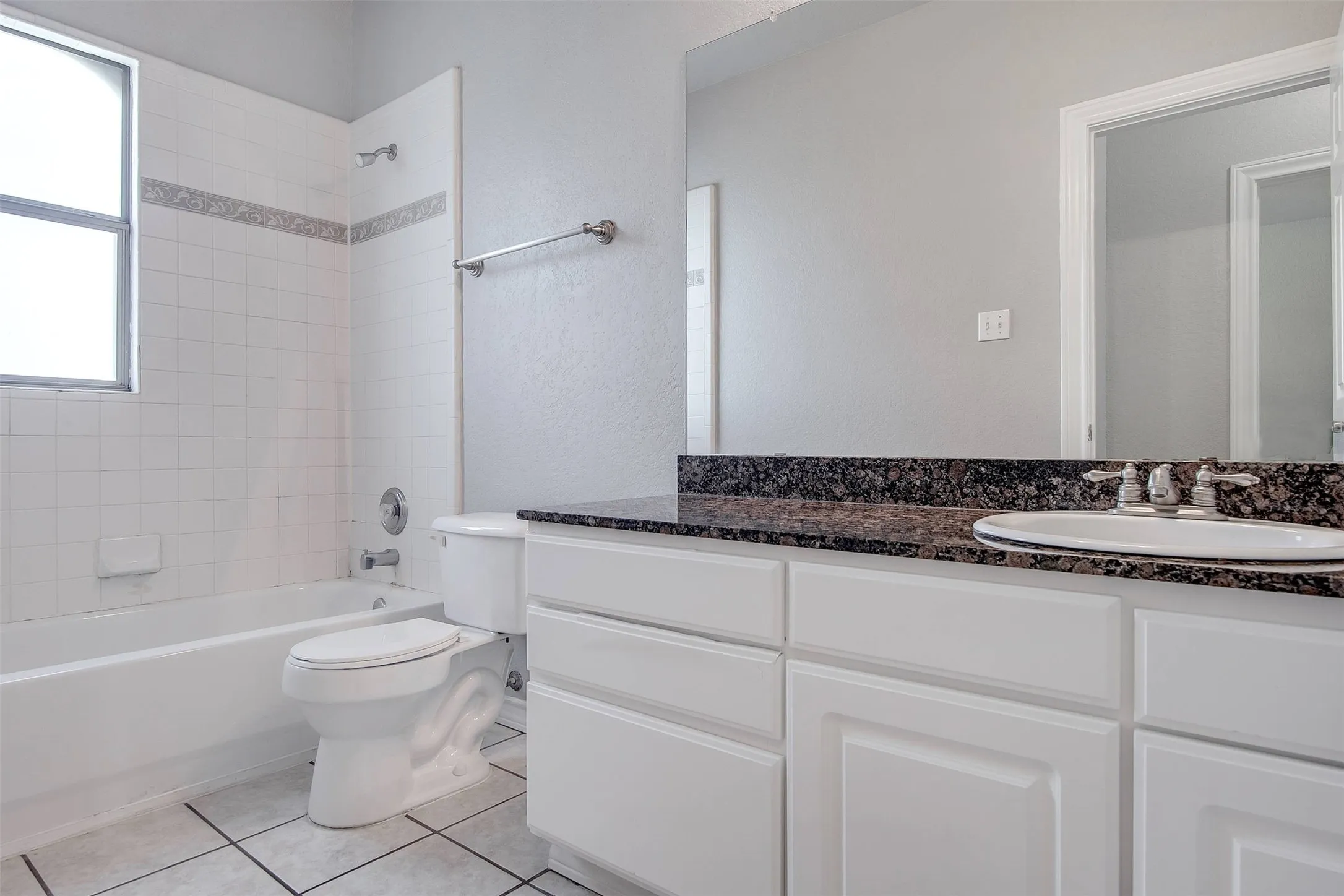 Bathroom featuring a white vanity with paneled cabinetry, dark speckled countertop, and an undermount sink with a chrome faucet