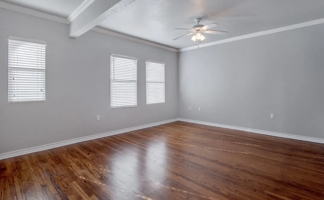 Spacious bedroom featuring wood-finish flooring, light gray wall paint, and white crown molding