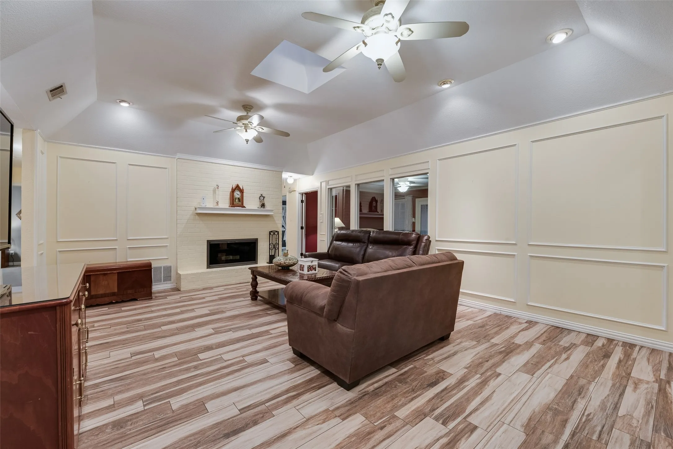 Large living room with picture frame paneling and skylight!