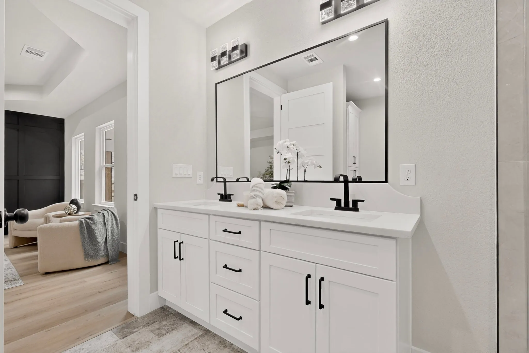 White dual vanity with integrated sinks, black hardware, and an oversized framed mirror