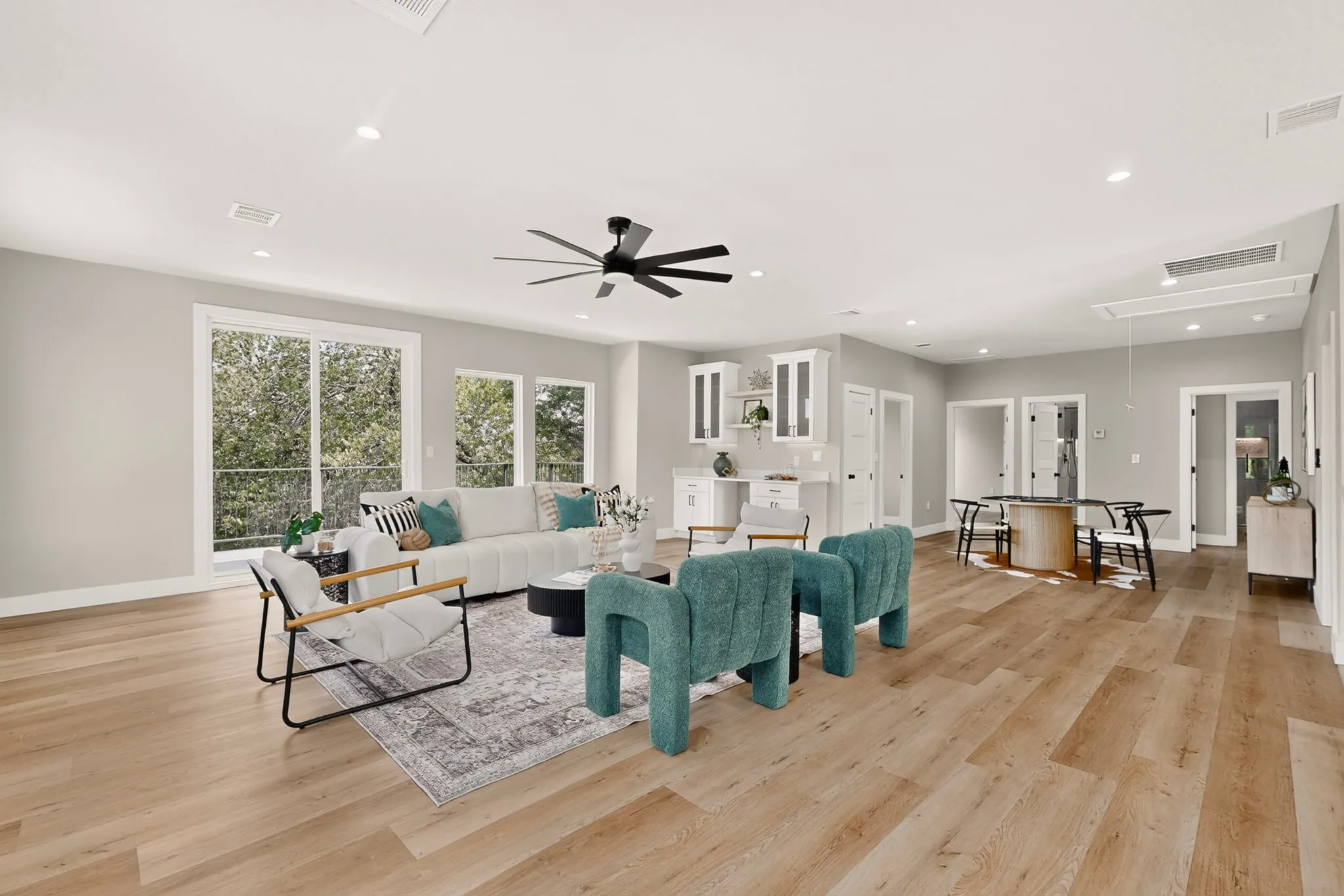 Spacious open-concept interior with wood-finish flooring, recessed lighting, and a contemporary ceiling fan