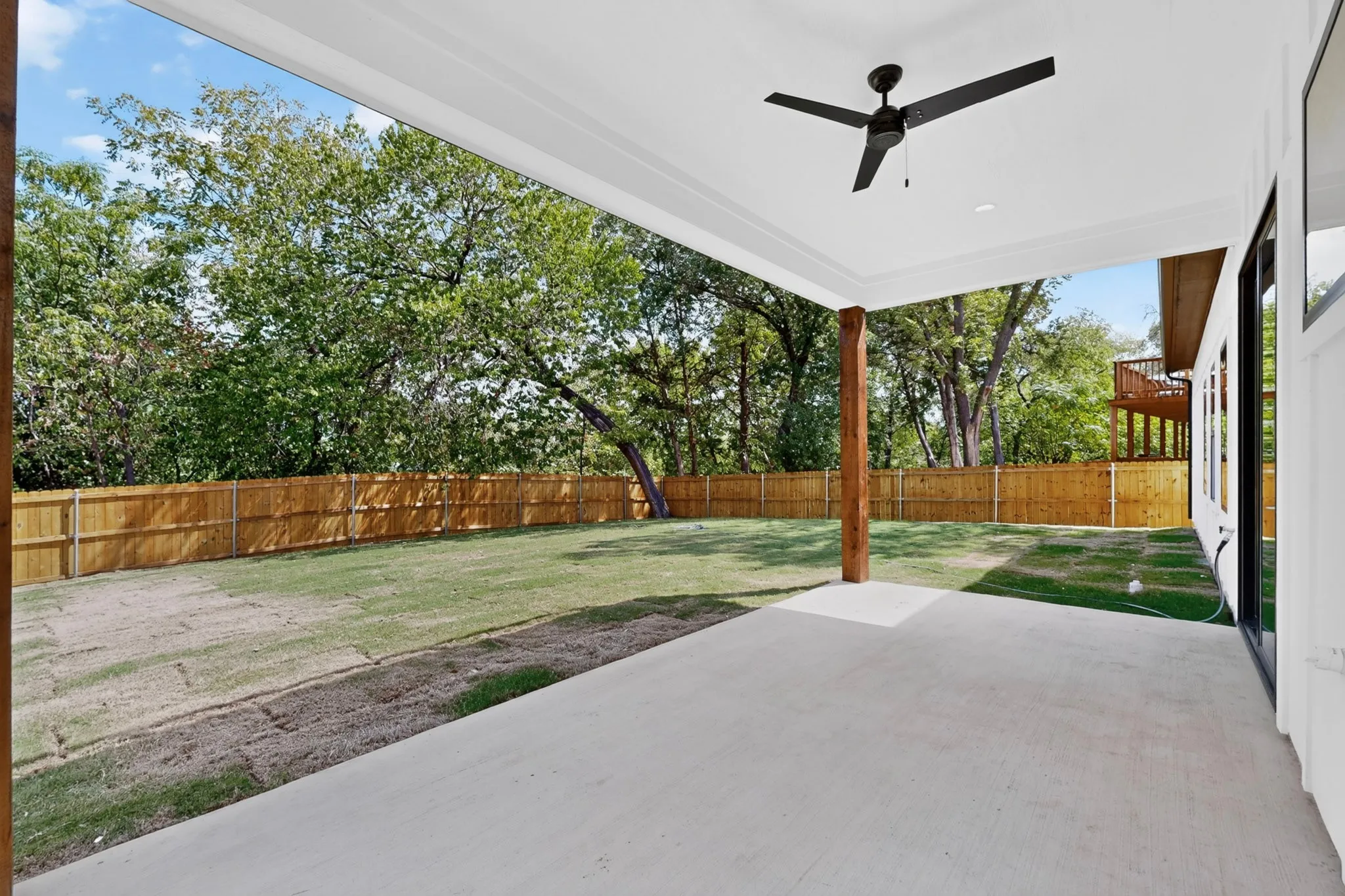 Covered patio with concrete flooring, wood support column, and a ceiling fan