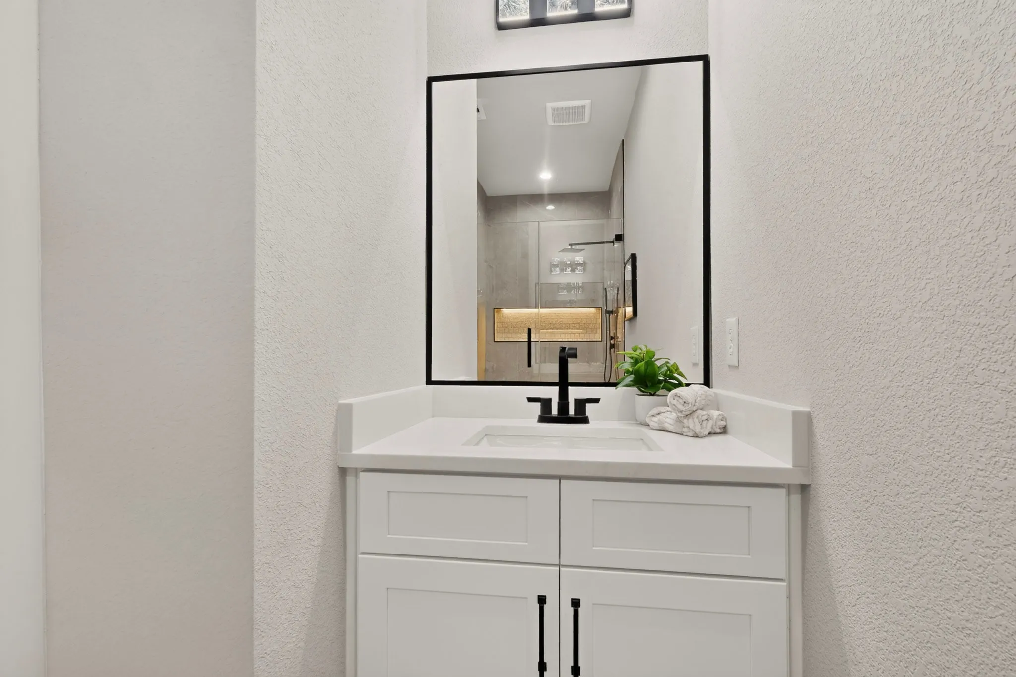 White vanity with shaker-style cabinetry, a built-in sink, and a matte black faucet
