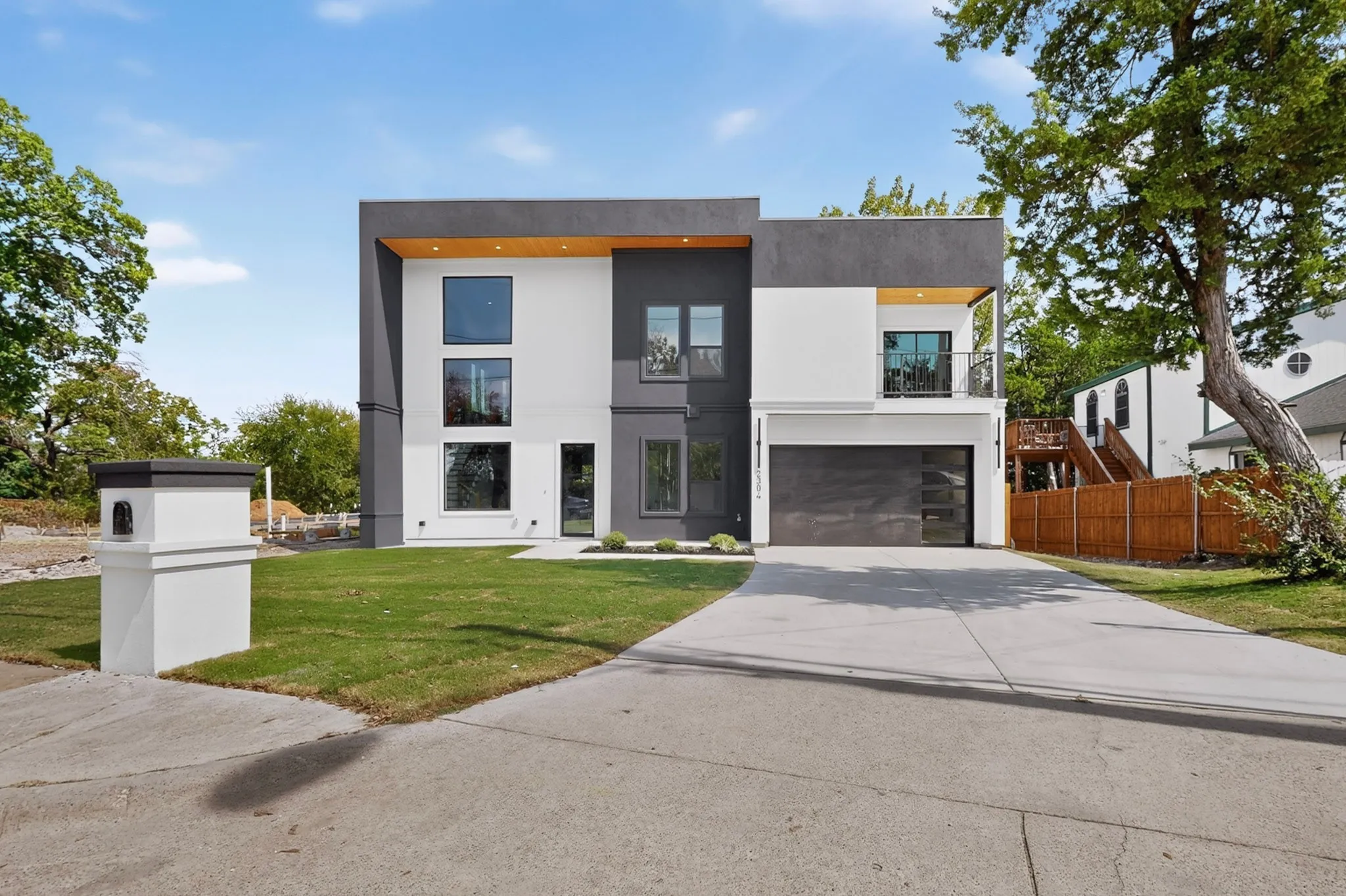 Modern architectural design with a flat roofline, multi-pane windows, and a concrete driveway